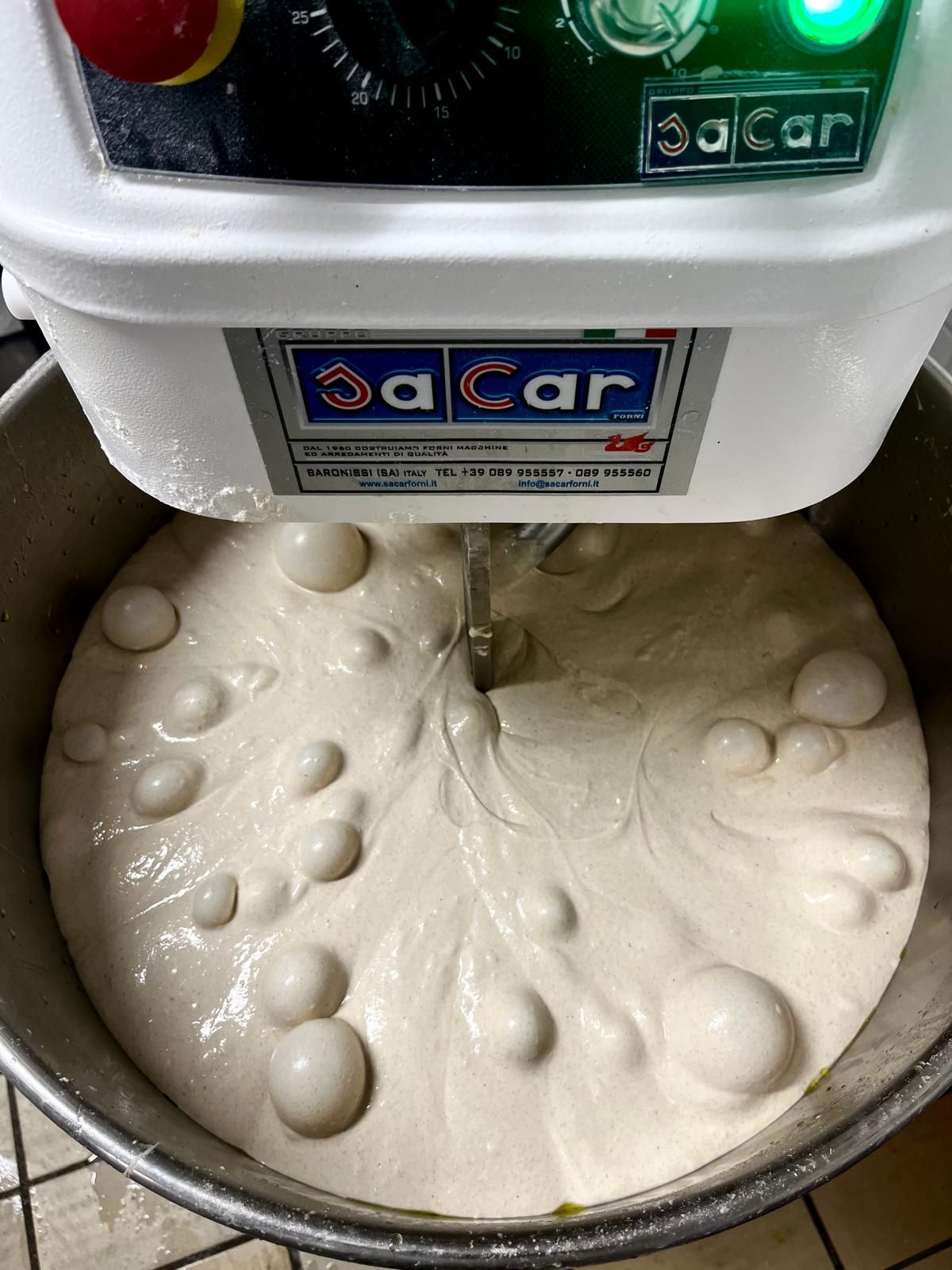 A JaCar commercial spiral mixer kneading smooth white bread dough in a large metal bowl.