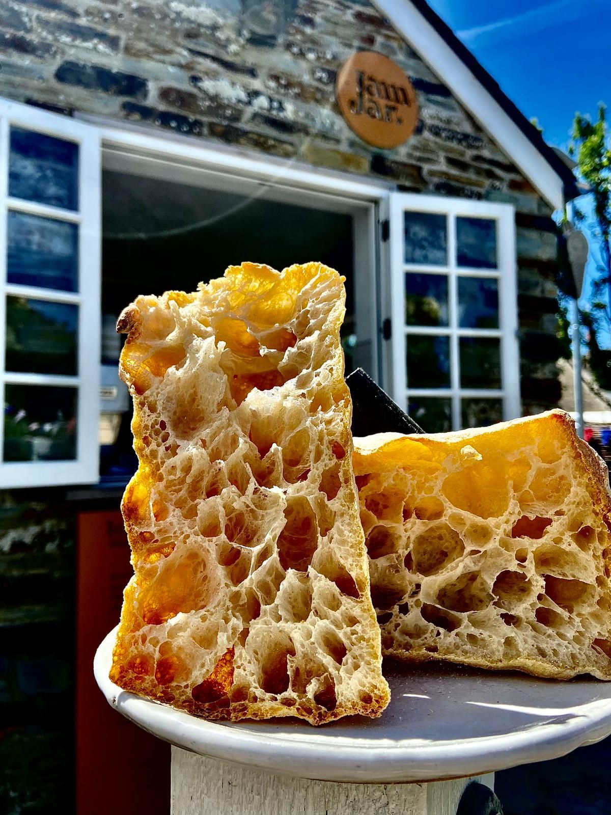Cross-section of artisan sourdough bread showing open honeycomb crumb structure displayed outside a stone bakery.