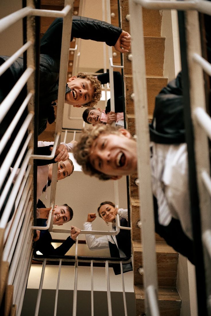 Group of smiling friends looking down through staircase railings in a fun candid photo.