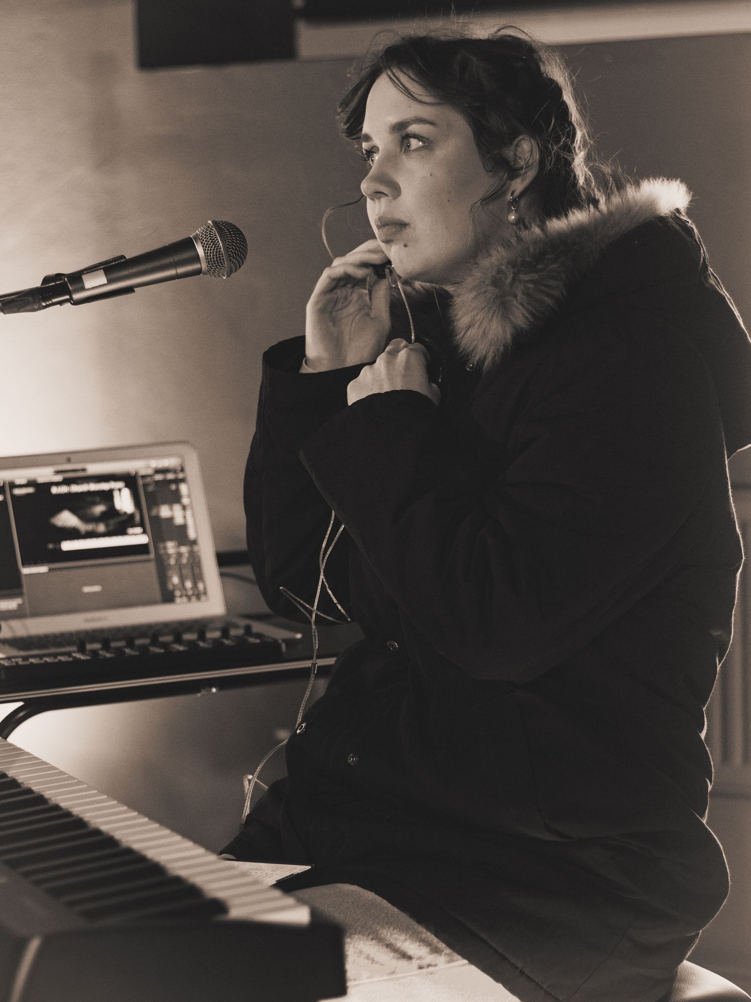Black and white image of a pianist adjusting her in-ear technology, ready to start playing.
