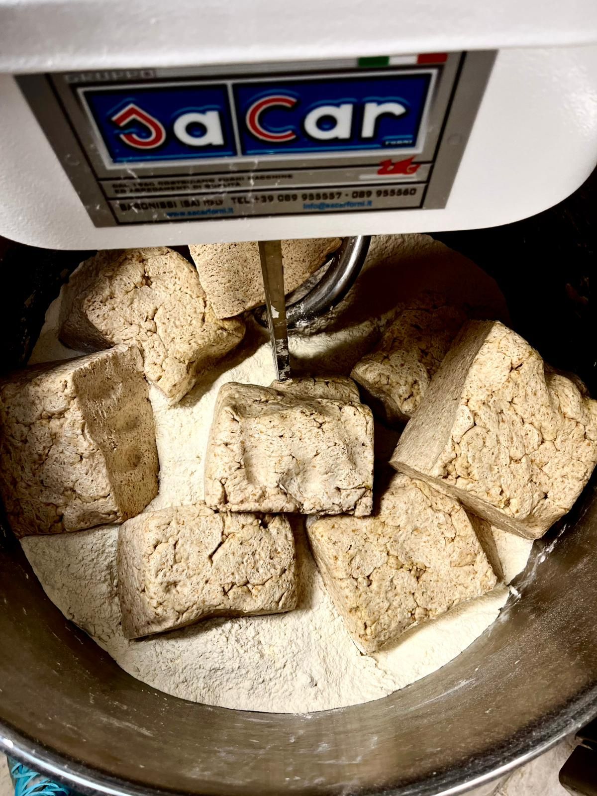 JaCar spiral dough mixer kneading fresh bread dough with yeast blocks in a professional bakery setting.