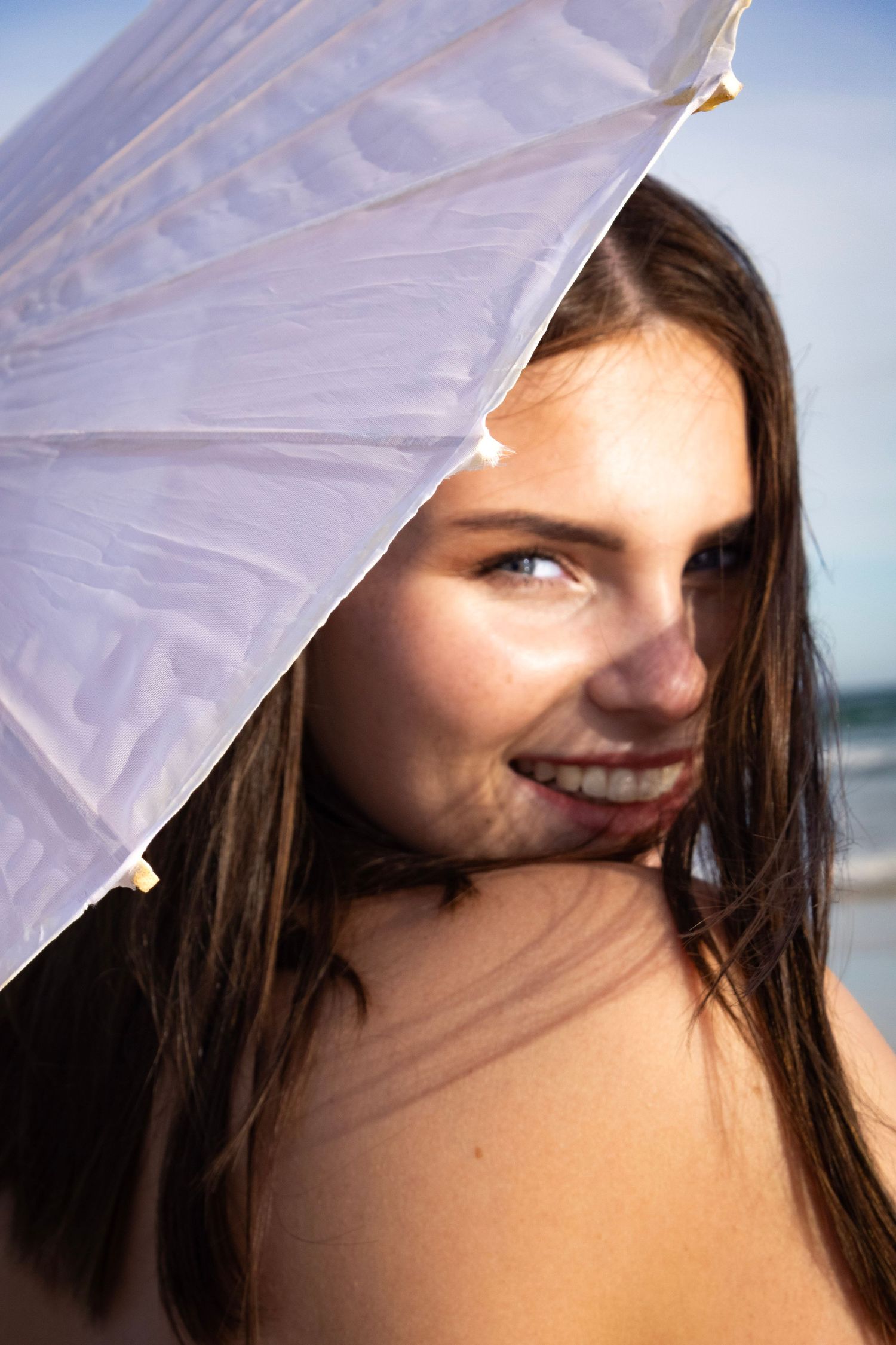 Portrait of a young woman smiling while holding an umbrella. Portrait photography at the beach Eastern Cape Jeffreys Bay.