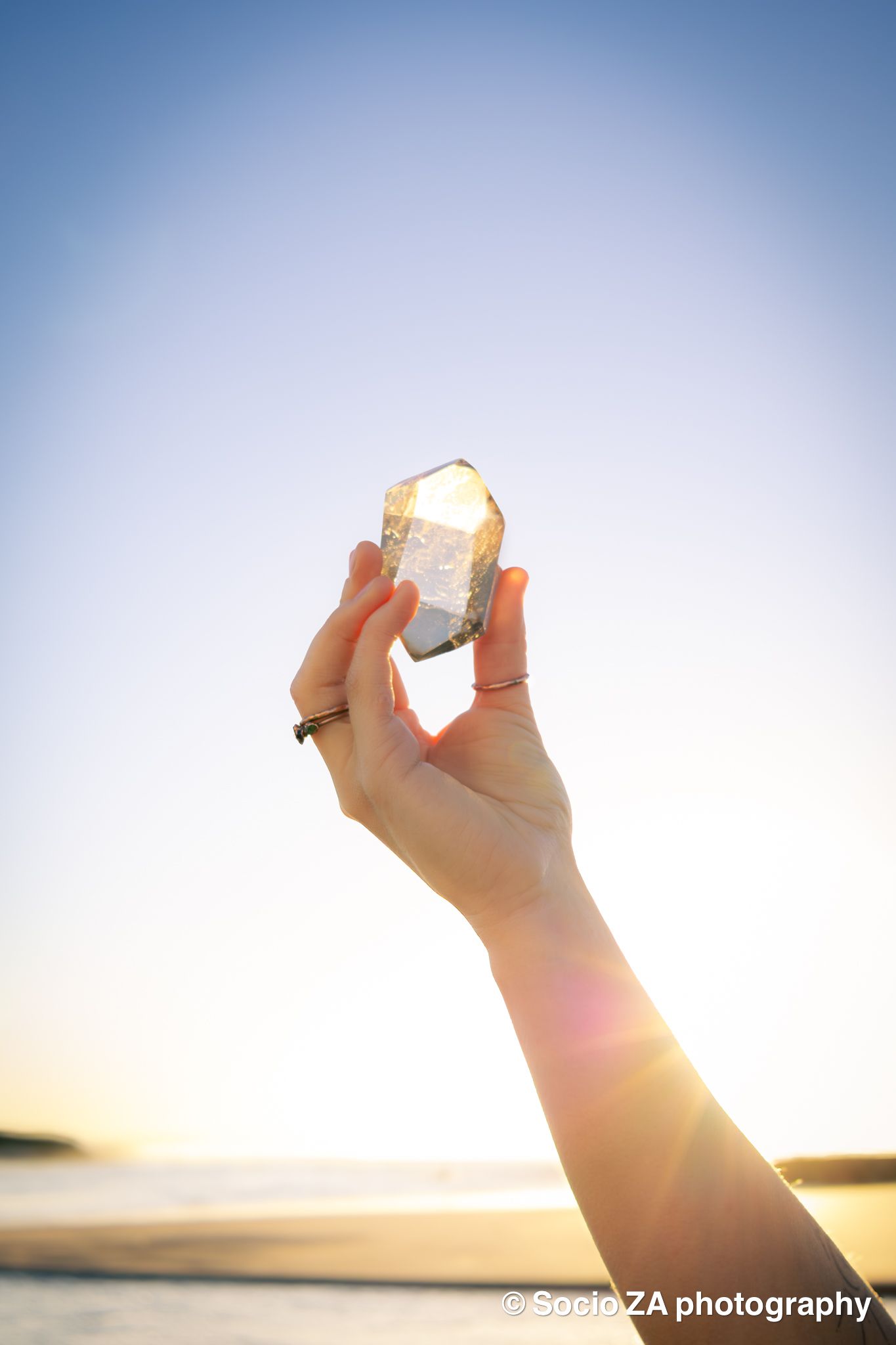 Portrait of a hand of a woman while holding a crystal at sunrise. Portrait photography at the beach Eastern Cape Jeffreys Bay.