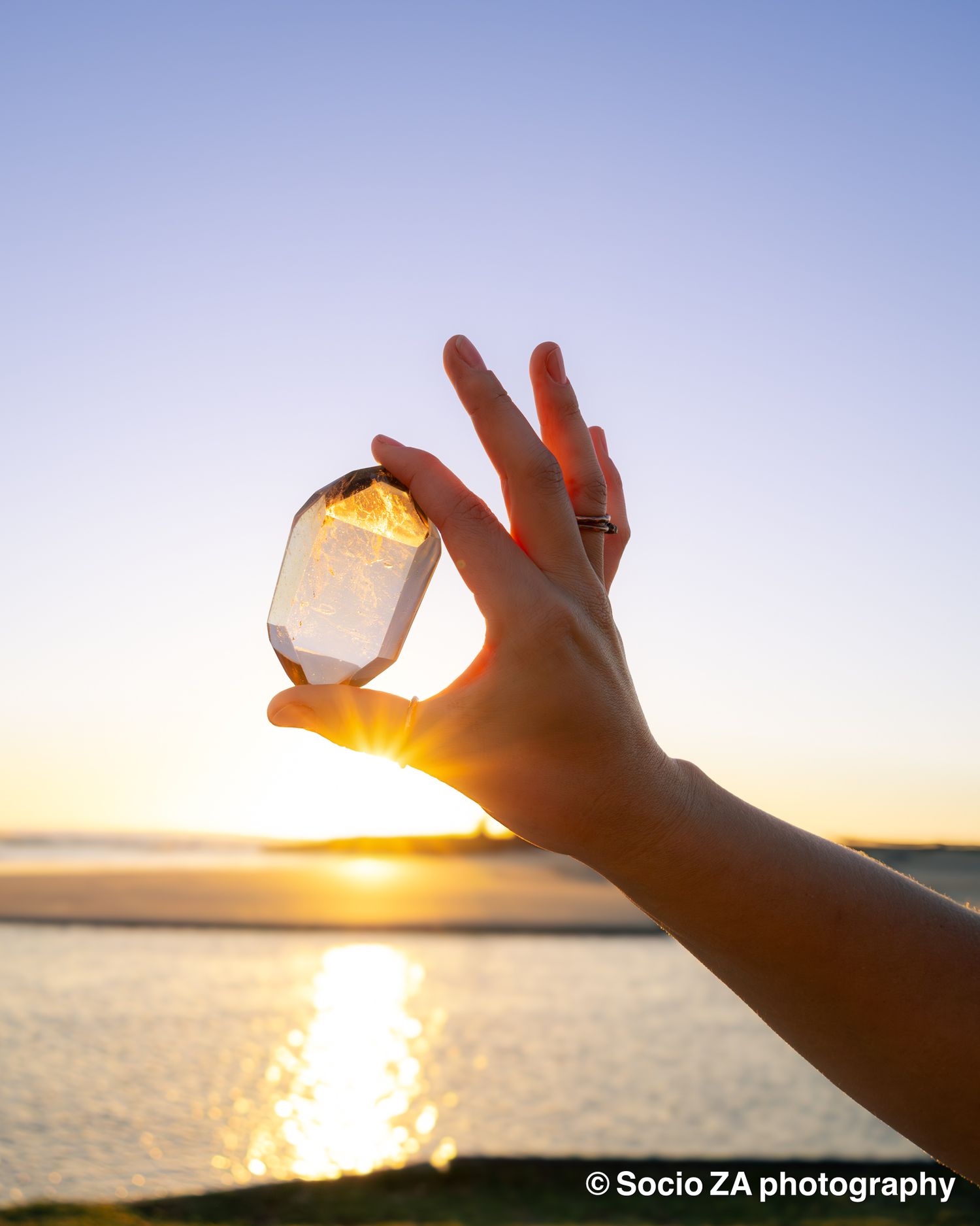 Portrait of a woman's hand holding a crystal at sunrise. Portrait photography at the beach Eastern Cape Jeffreys Bay.