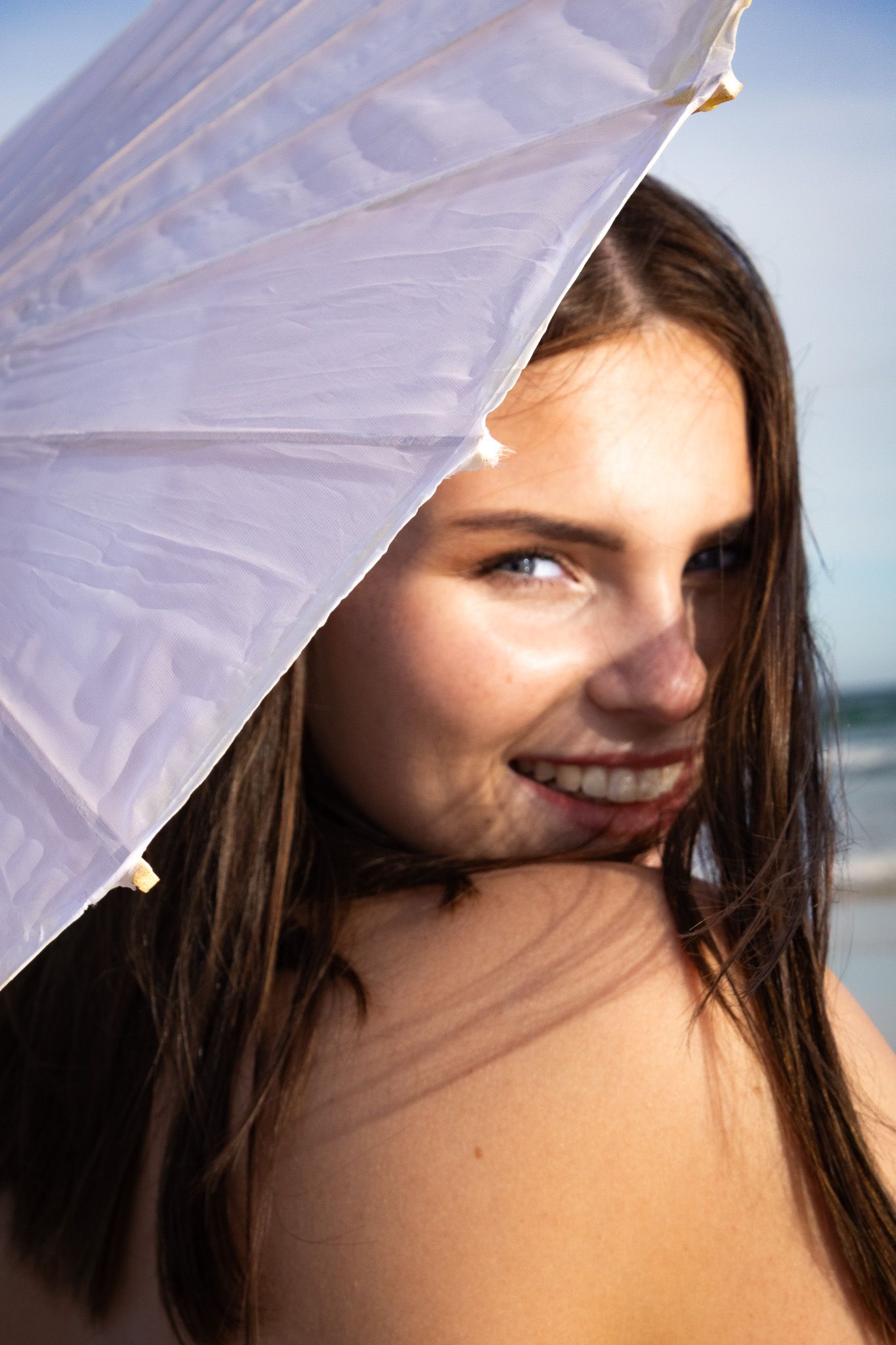 Portrait of a young woman smiling while holding an umbrella. Portrait photography at the beach Eastern Cape Jeffreys Bay.