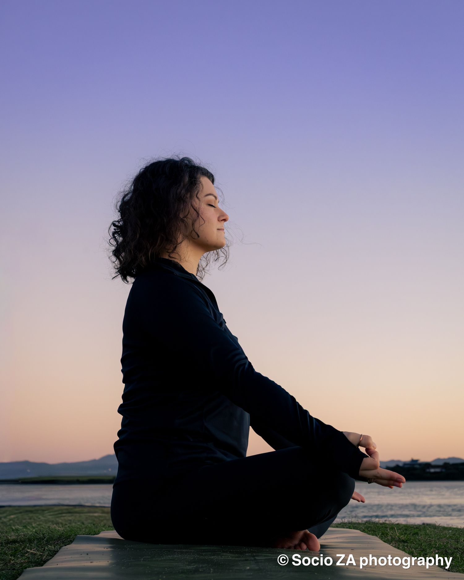 A woman doing a yoga pose at sunrise at the beach with the water and sun behind her. Eastern Cape St Francis Bay