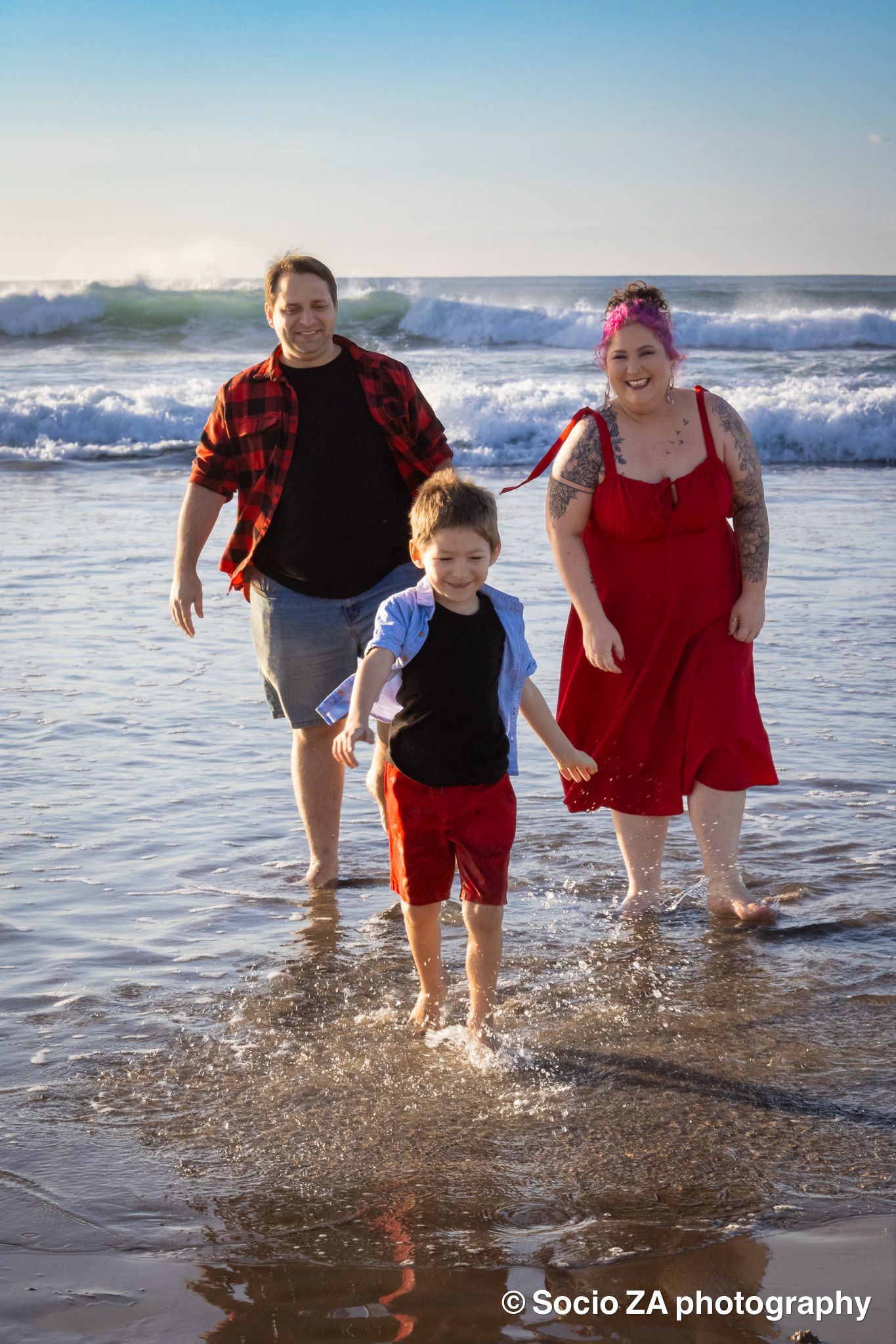 Family running on the beach in the water in Eastern Cape Jeffreys Bay. Family photography. Children playing on the beach in the surf.