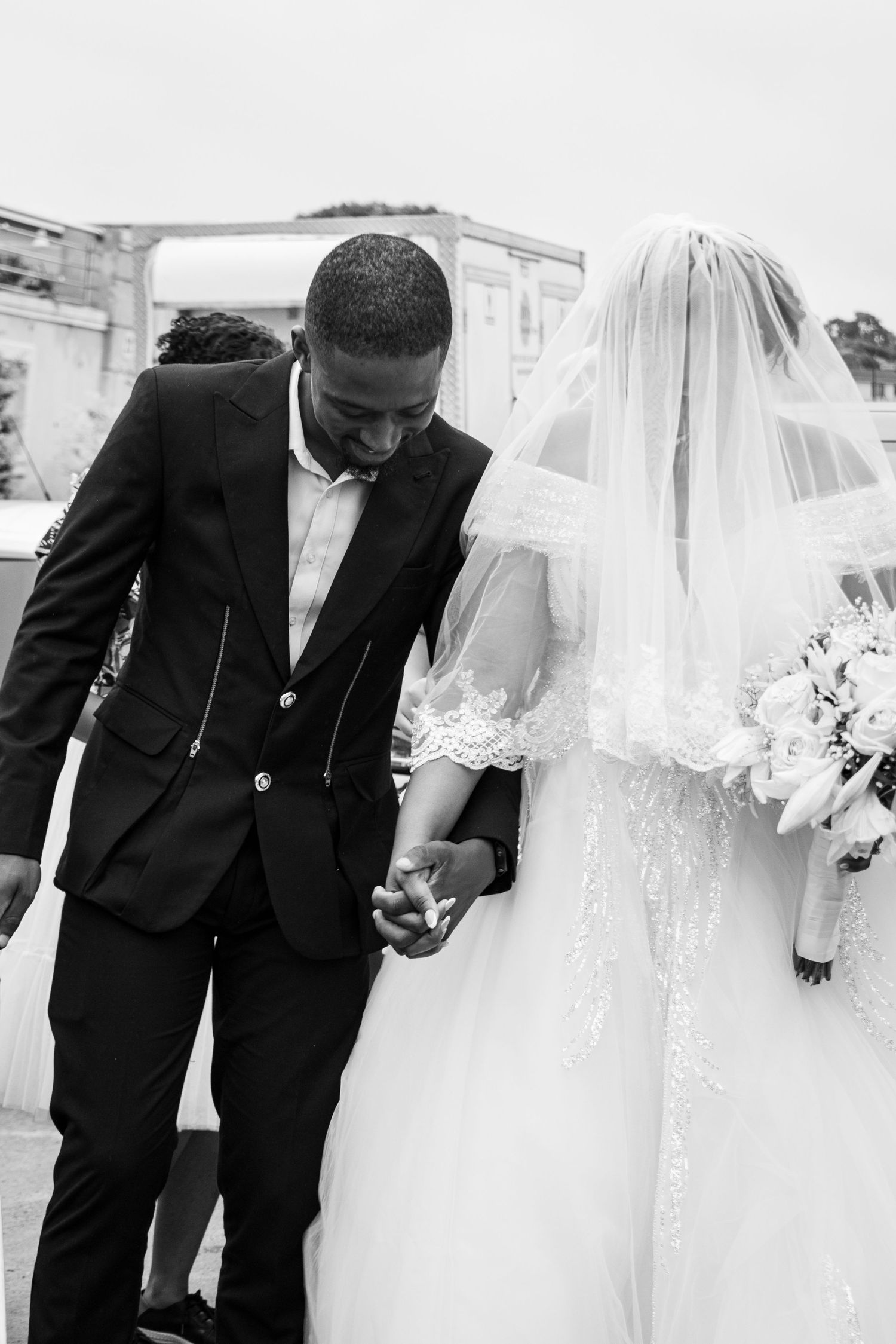 The groom holds the bridge as they walk towards the reception area. A white wedding held in Durban, KwaZulu-Natal.