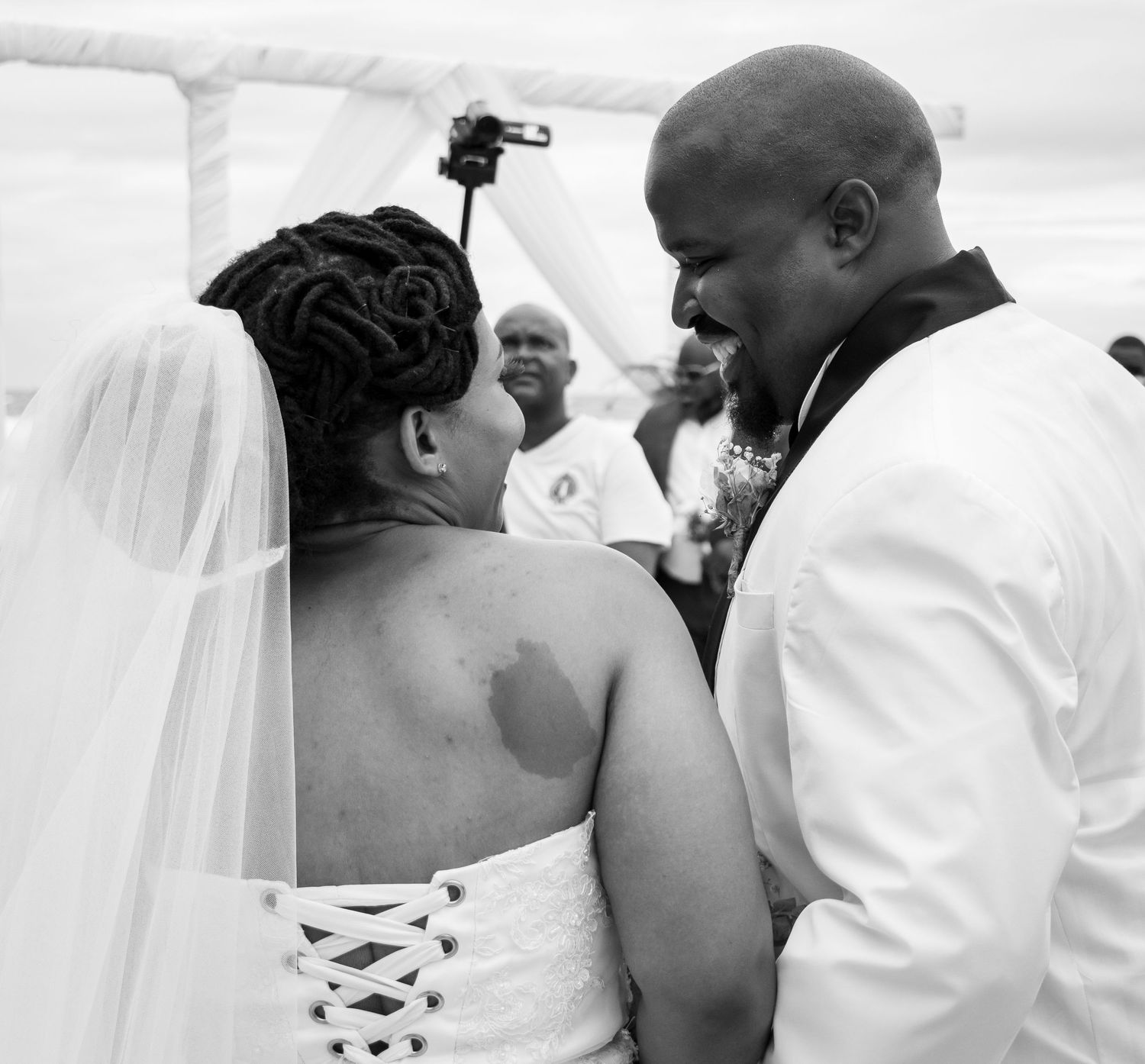 All smiles as the couple smile at each other during their white wedding ceremony.