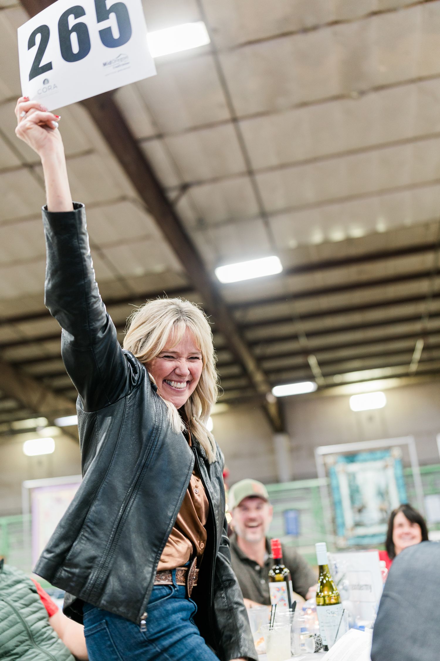 A woman holding up her bid paddle at an auction in Prineville, Oregon