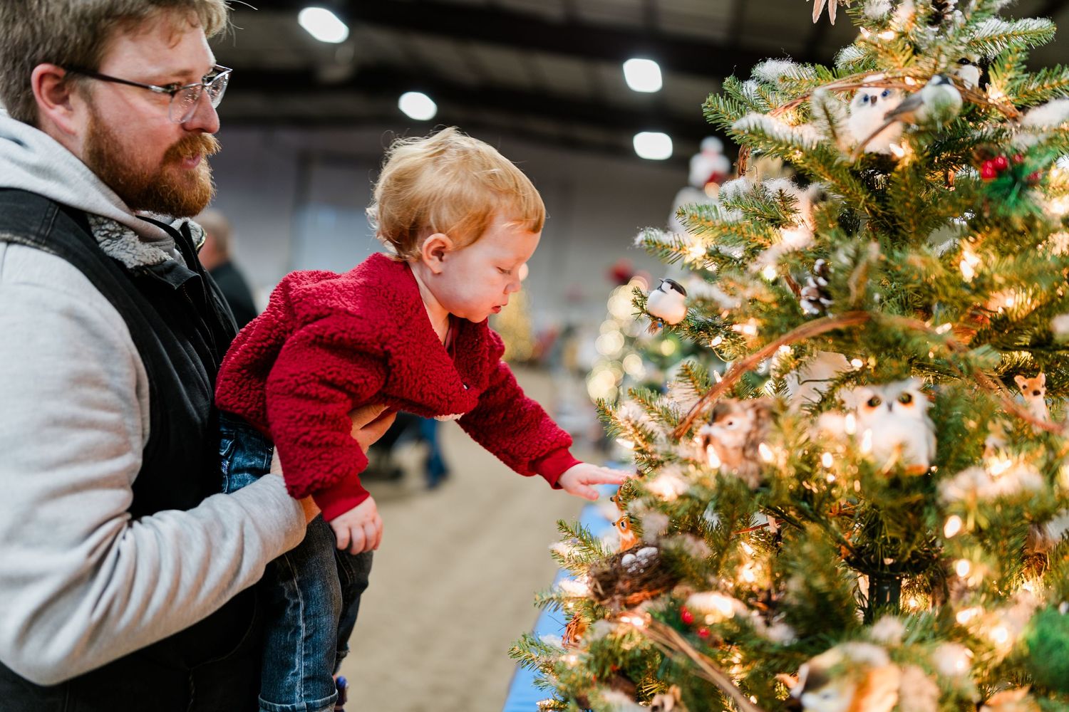 A man holding his child by a Christmas tree at an event in Prineville, Oregon