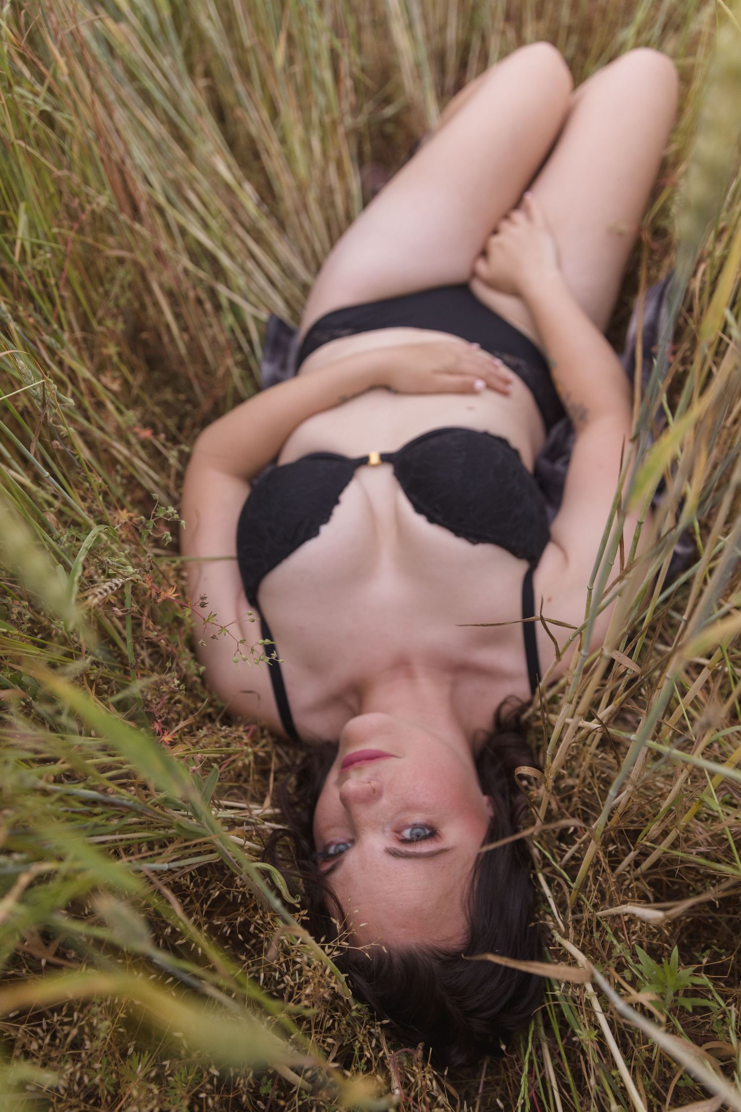 Intimate outdoor portrait in black lingerie among tall grass.