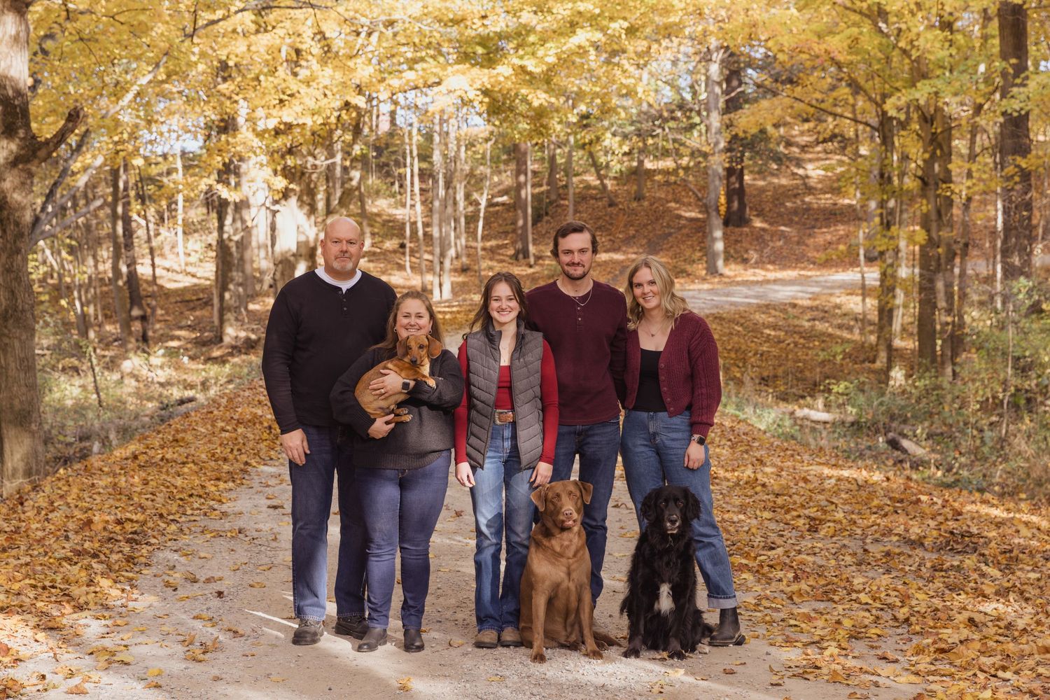 Group portrait with a golden retriever in a rustic autumn setting.