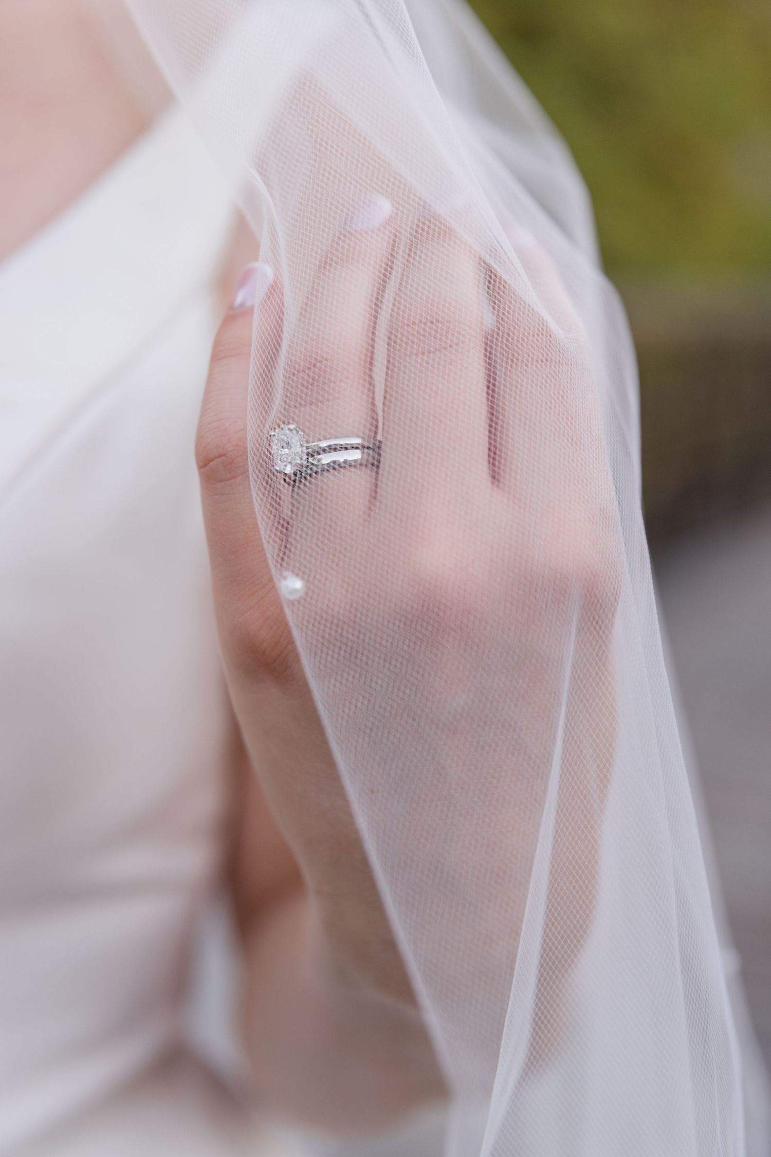 Diamond engagement ring and wedding band shown through delicate white bridal veil.