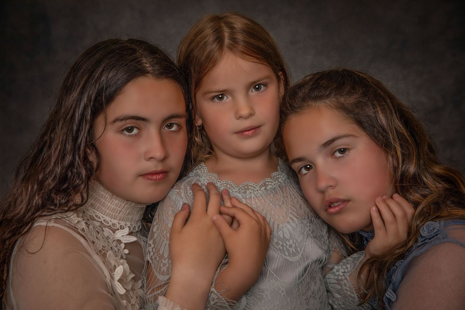 Three figures in vintage-style dresses pose together in an artistic portrait.
