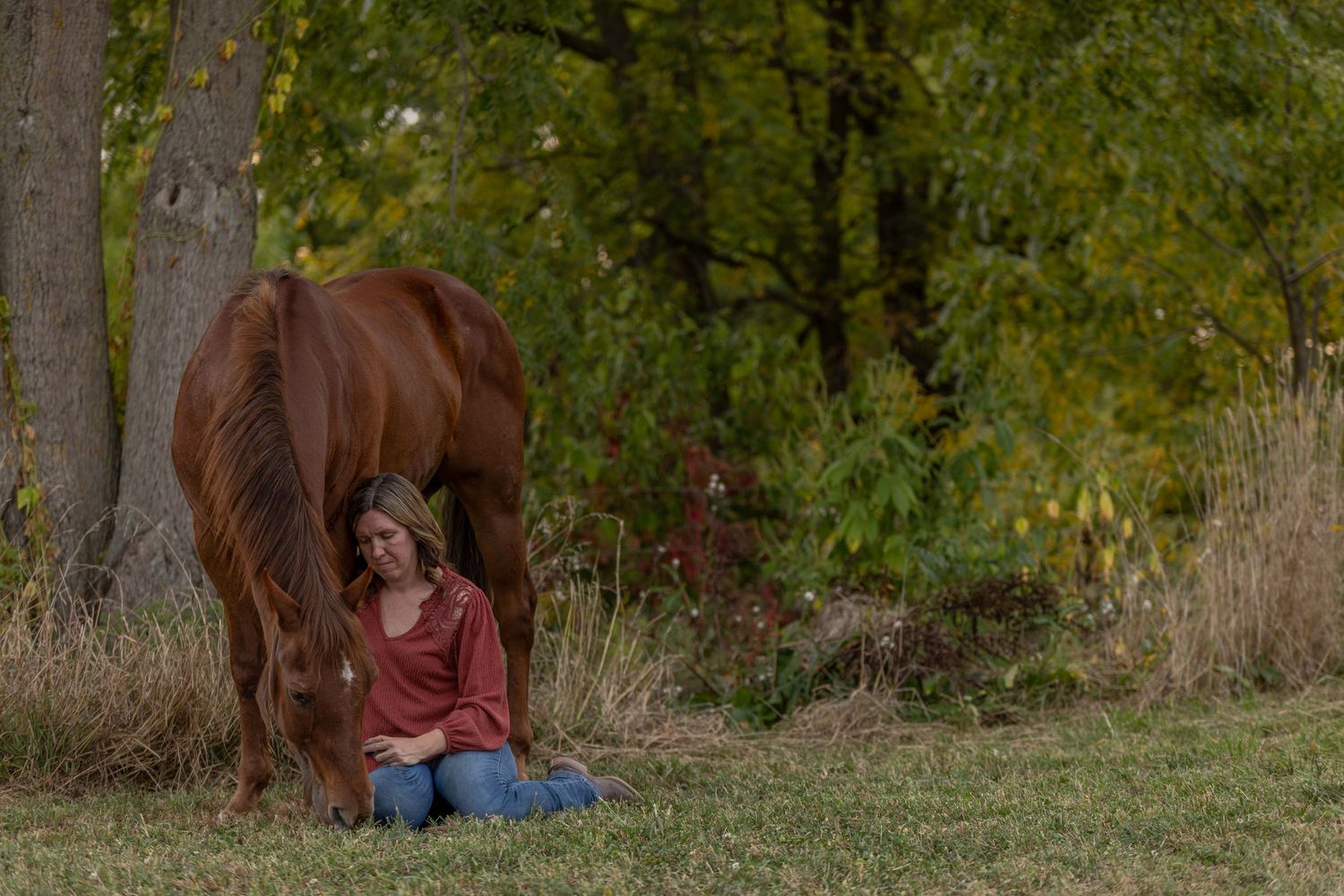 Horse and owner portraits taken in a wooded area with autumn foliage.