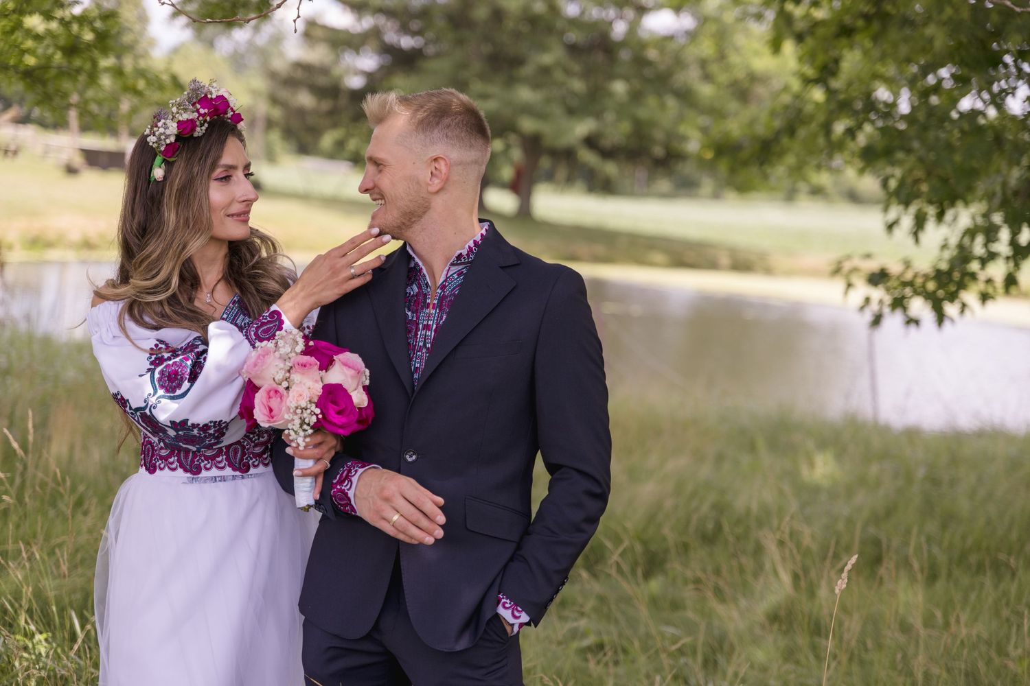 Close-up details of purple and pink floral embroidery patterns on white traditional wedding attire.
