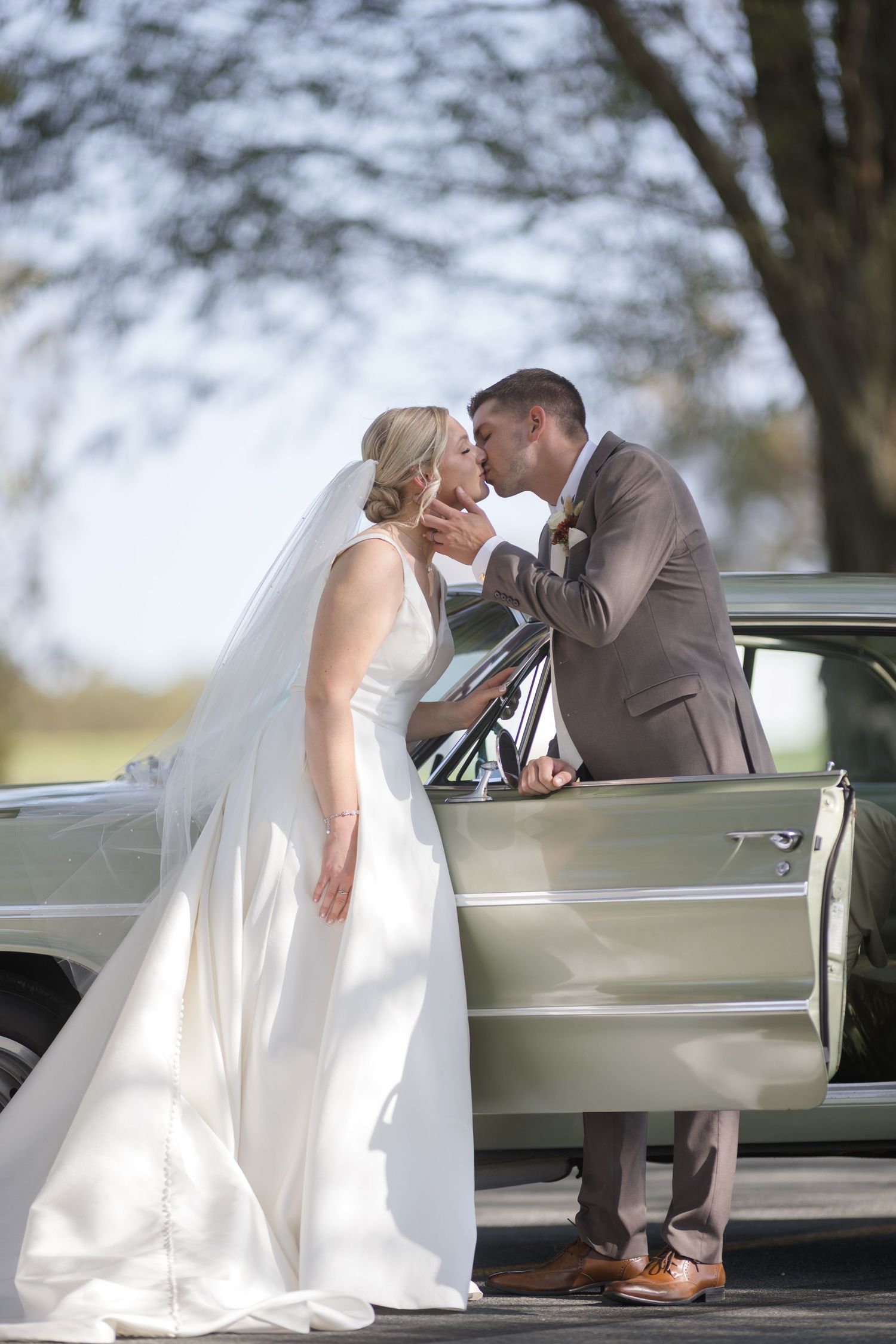 Romantic wedding portraits with vintage car featuring flowing white dress and classic styling.