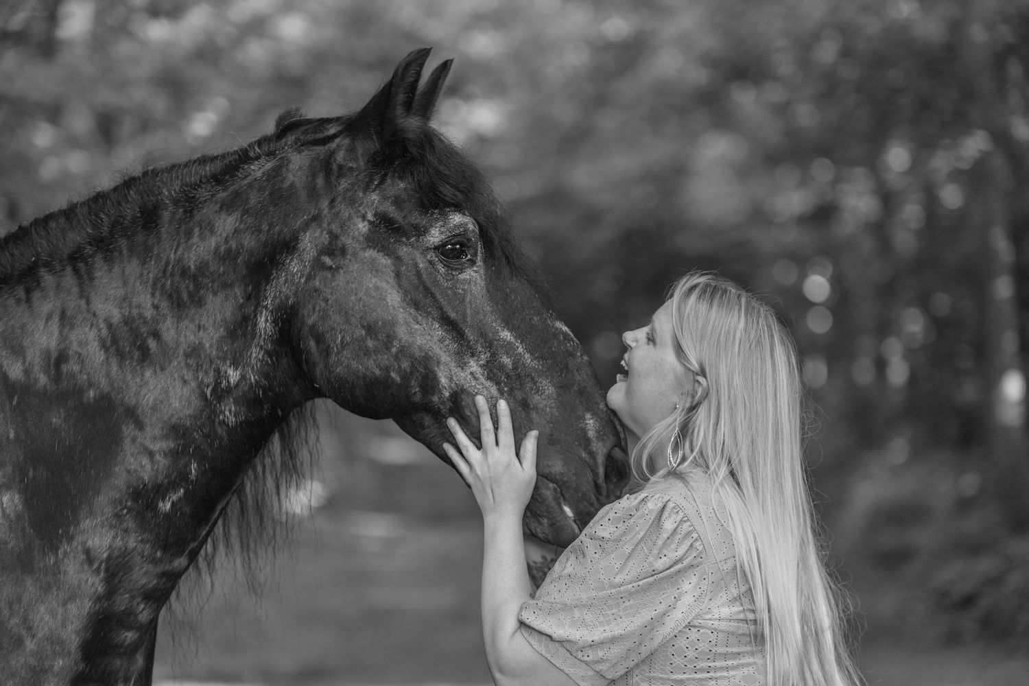 Black and white photo of a horse and person sharing an intimate bonding moment.