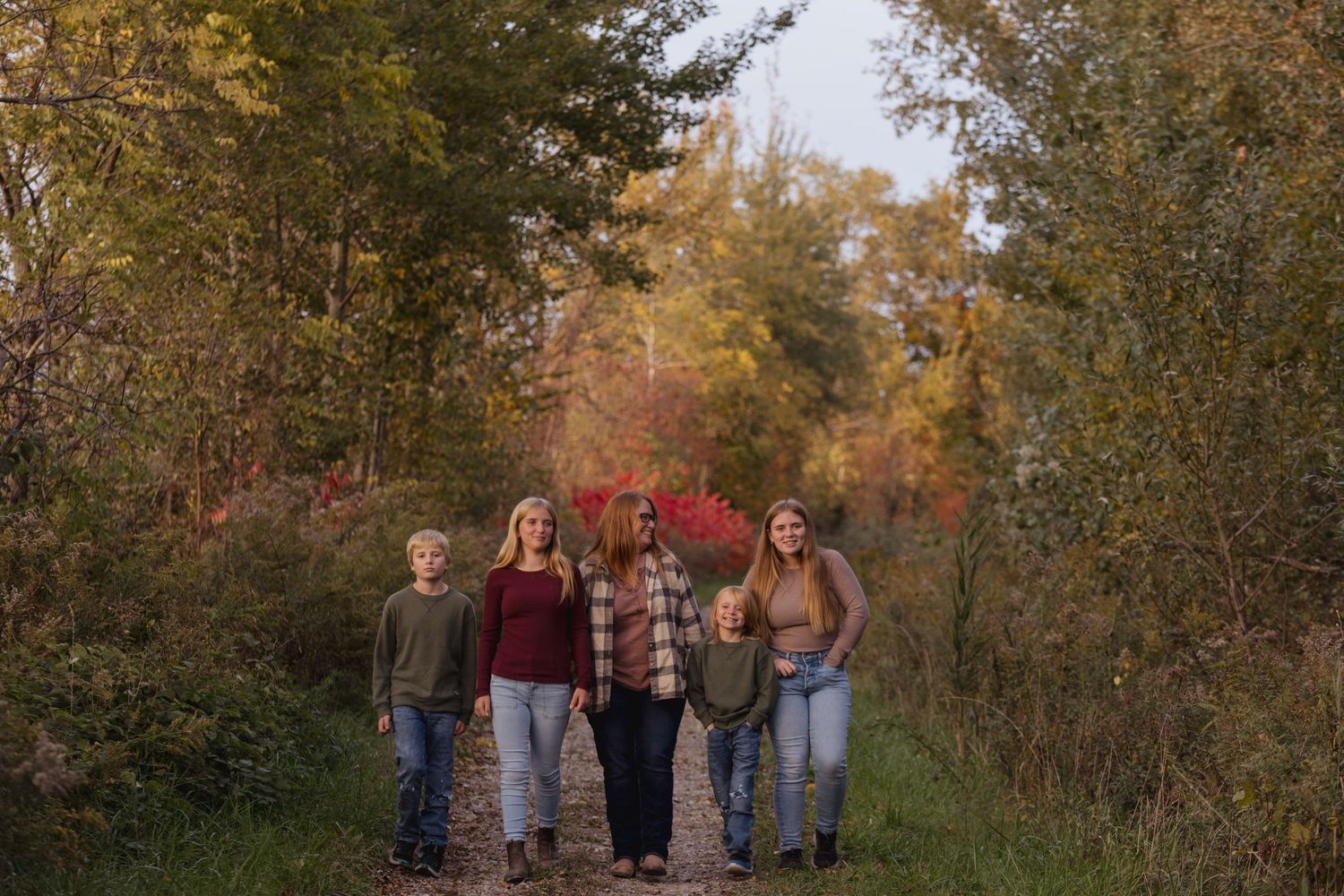 Family walking together through a wooded path during autumn.