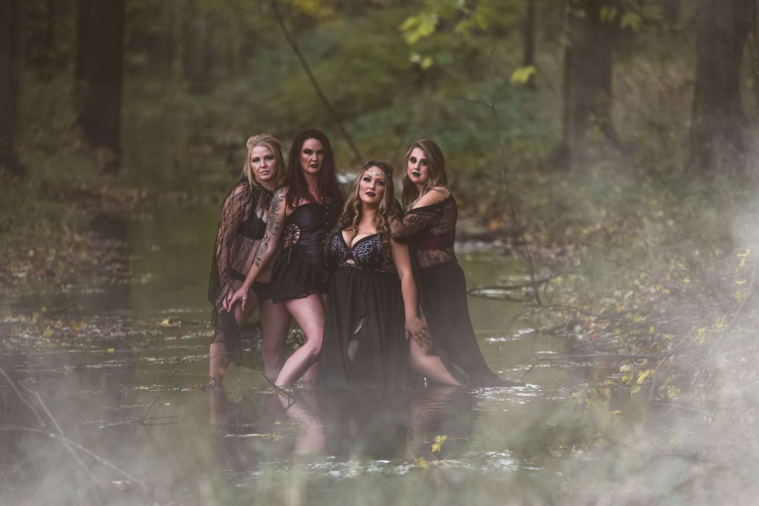 Friends enjoying a playful photoshoot by a stream in a wooded area.