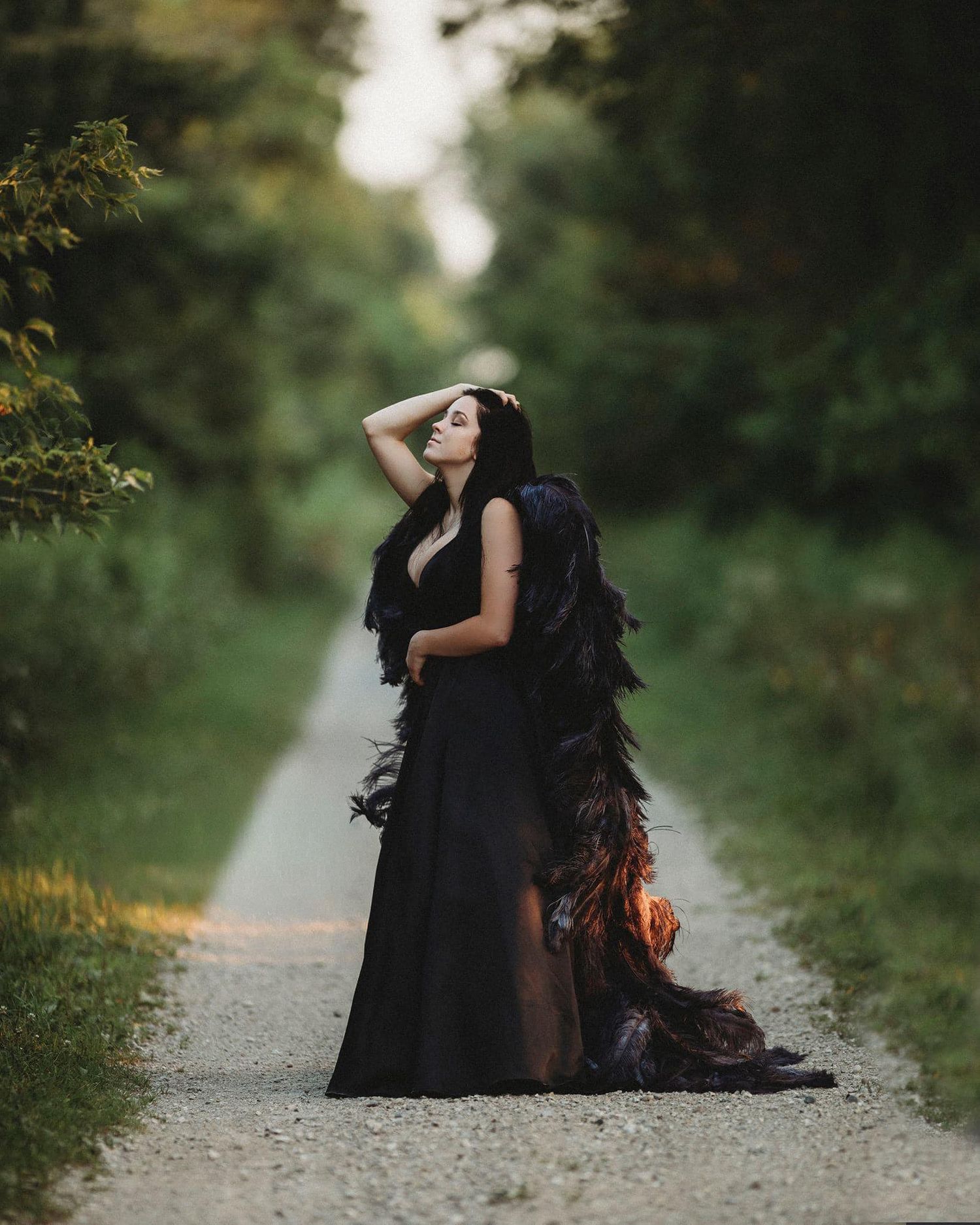 Figure in black dress sitting on a path surrounded by lush greenery in an artistic photoshoot sequence.