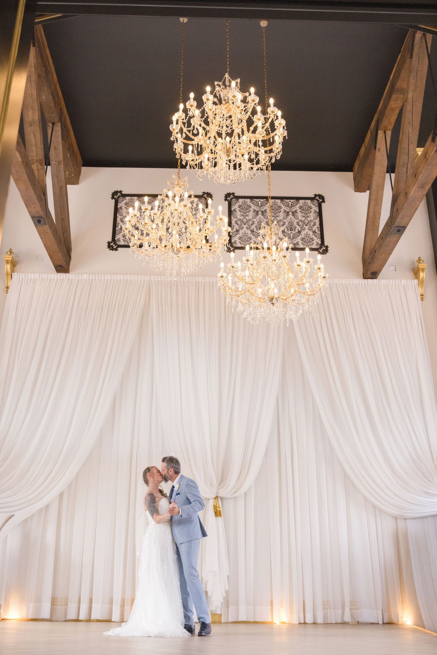 Elegant ballroom with crystal chandeliers and white draping for a wedding reception.