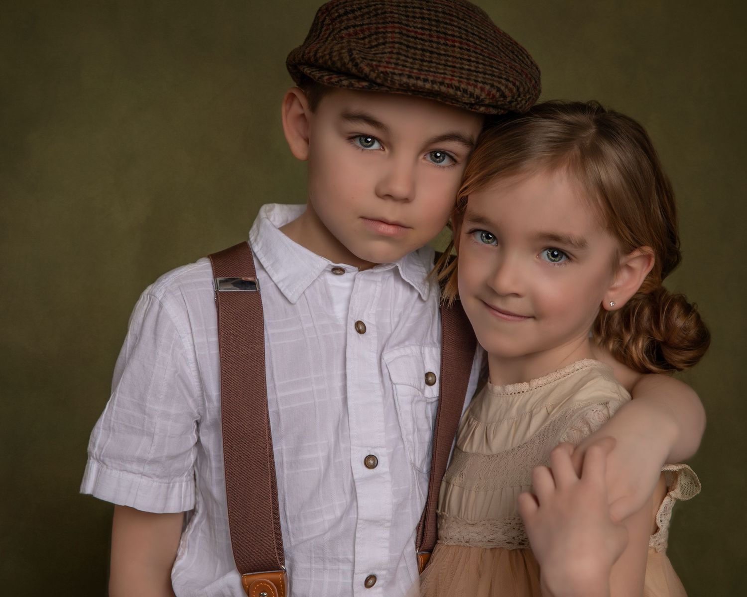 Vintage-inspired portrait of two children in period clothing with suspenders and newsboy cap.