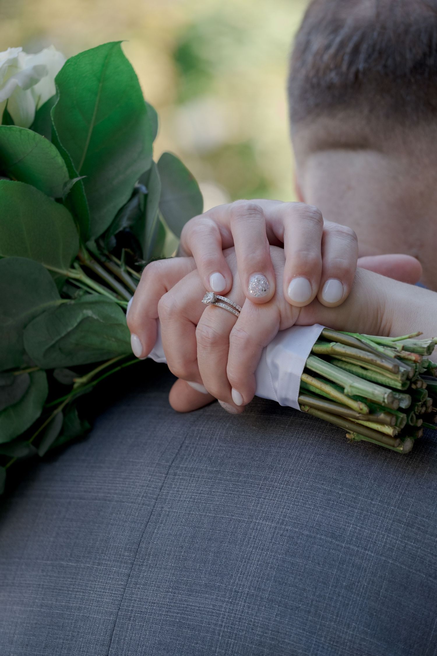 Close-up of hands holding flower stems against grey fabric background.