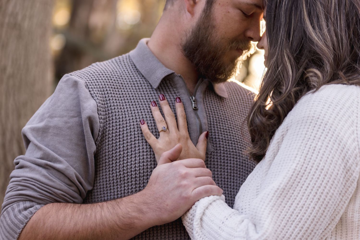 A romantic engagement session outdoors with a couple embracing in natural lighting.