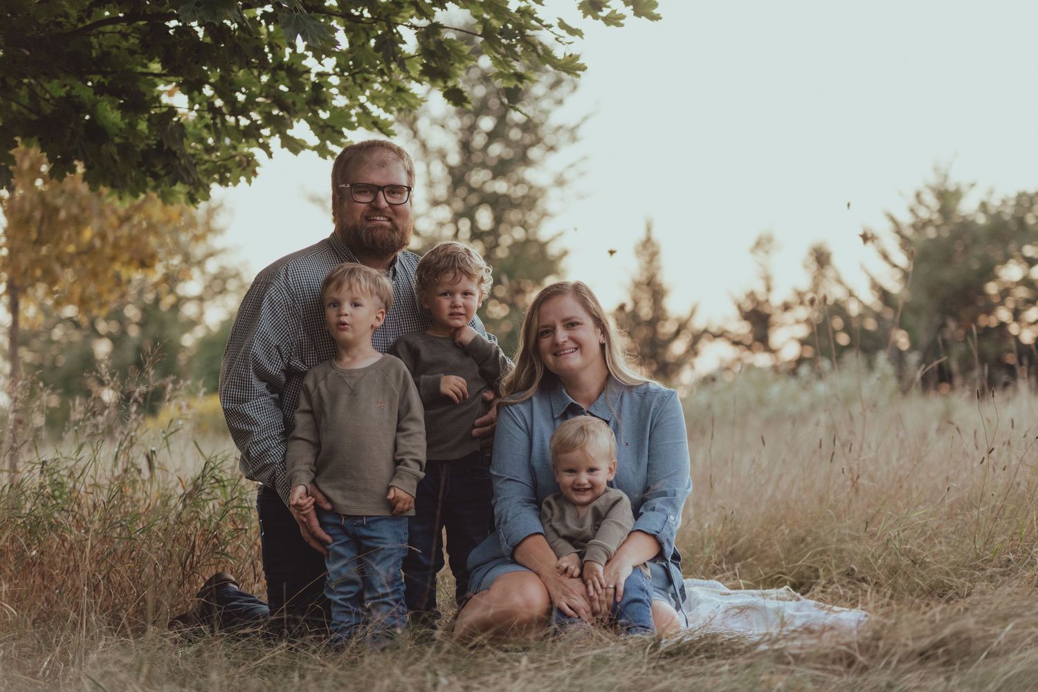 Family enjoying tender moments in a golden sunlit field.