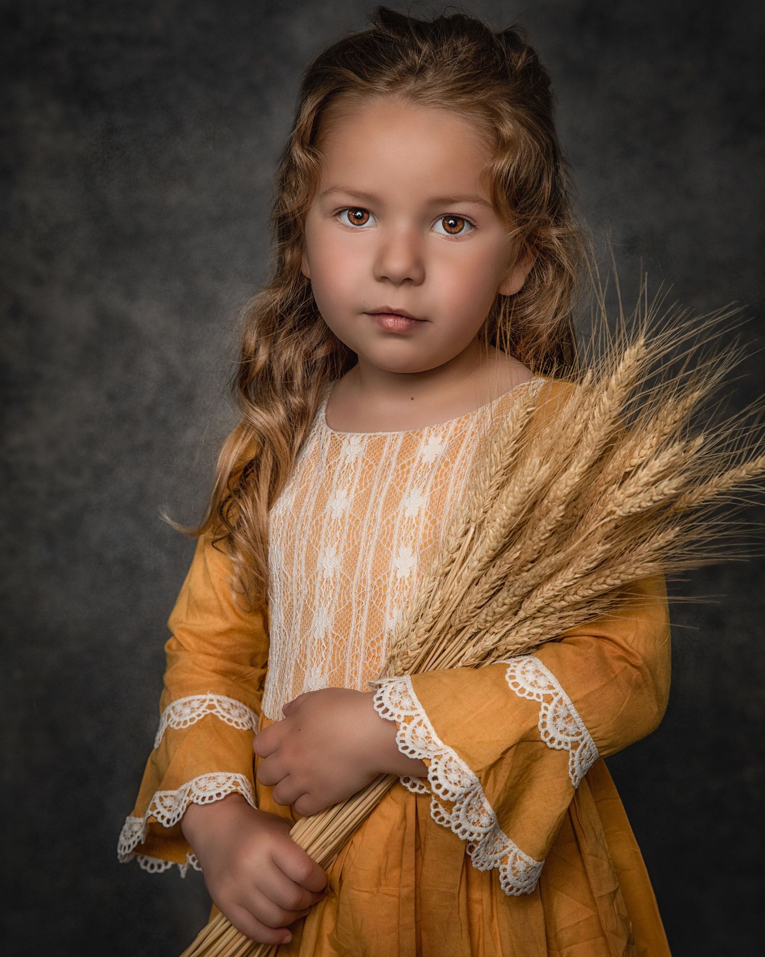 Portrait of a young figure in a mustard-colored dress holding wheat stalks against a dark background.