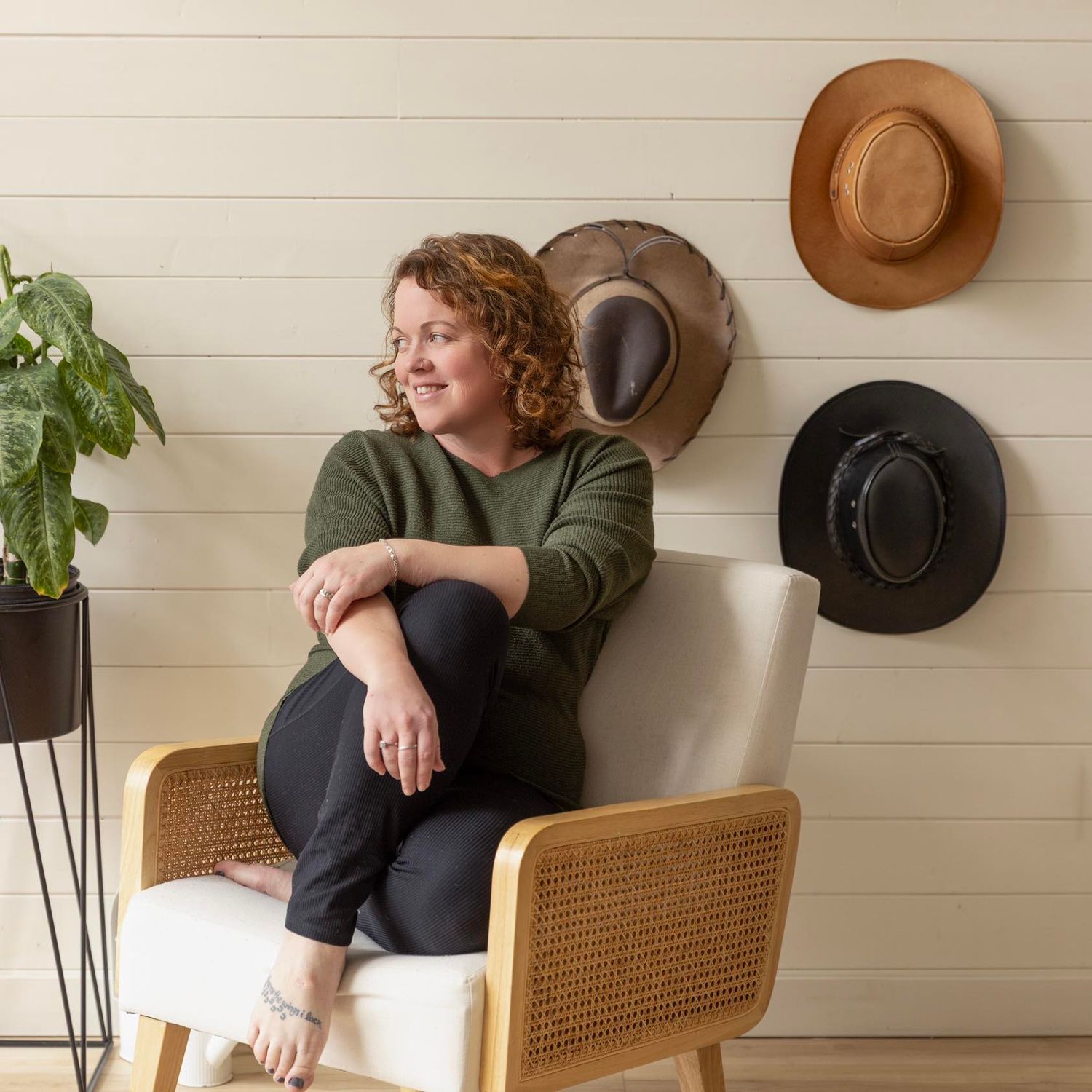 A modern lifestyle portrait session with woven cane chairs and decorative hats on shiplap walls.
