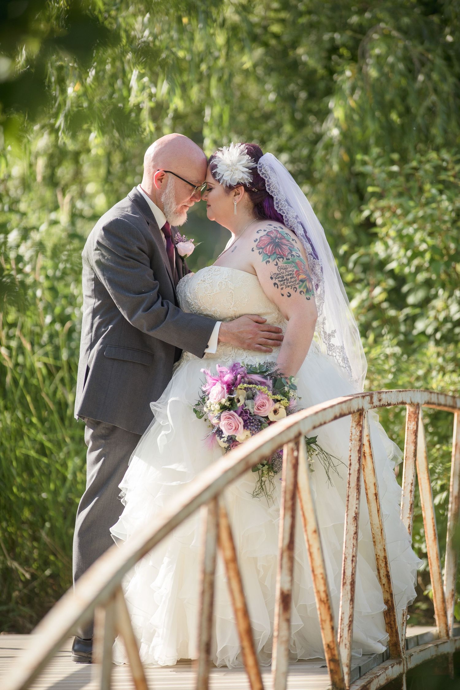 A romantic wedding moment on a rustic wooden bridge surrounded by lush greenery.