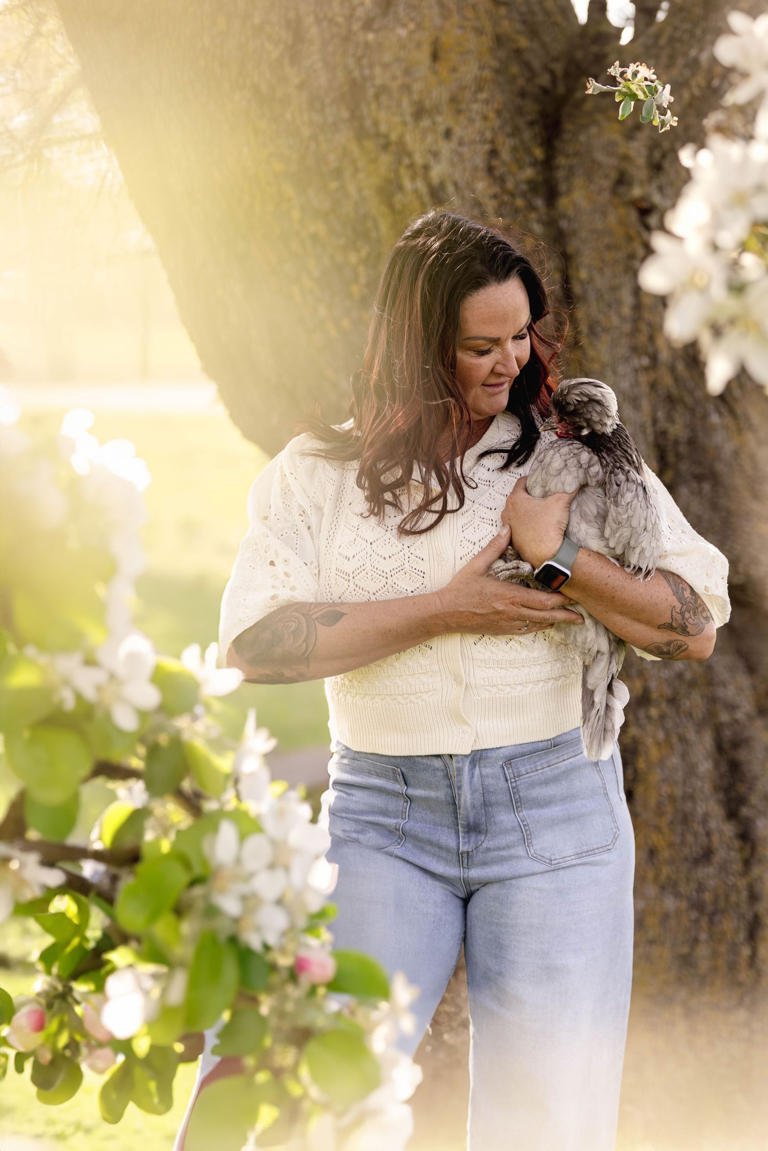 Spring portrait session among blooming tree branches with soft golden lighting.