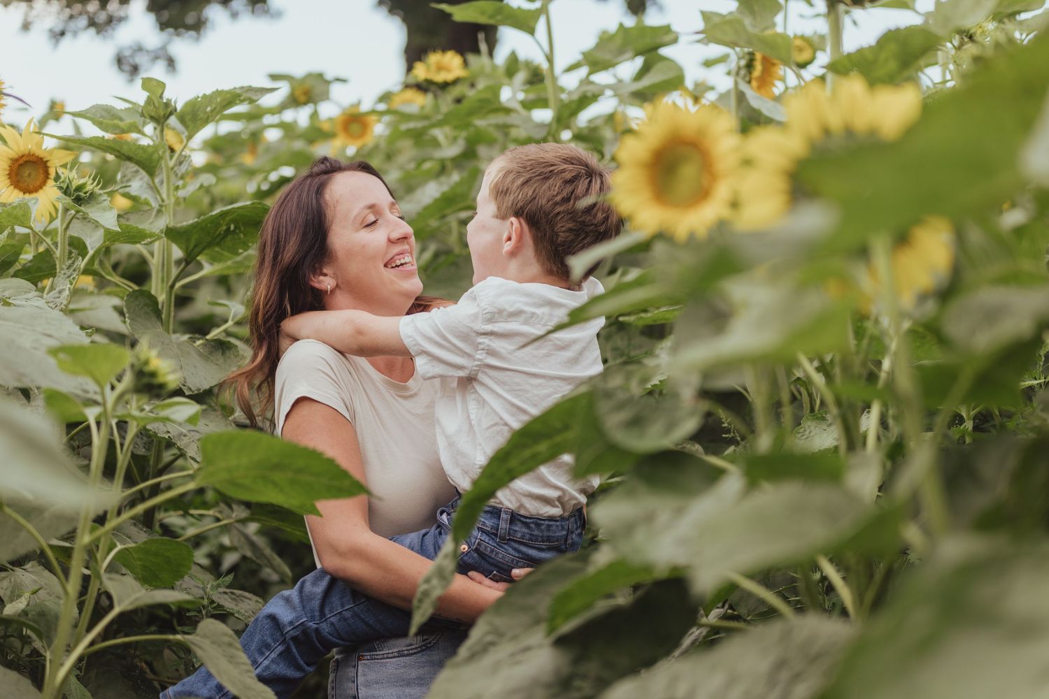 Mother and child sharing joyful moments among blooming sunflowers.