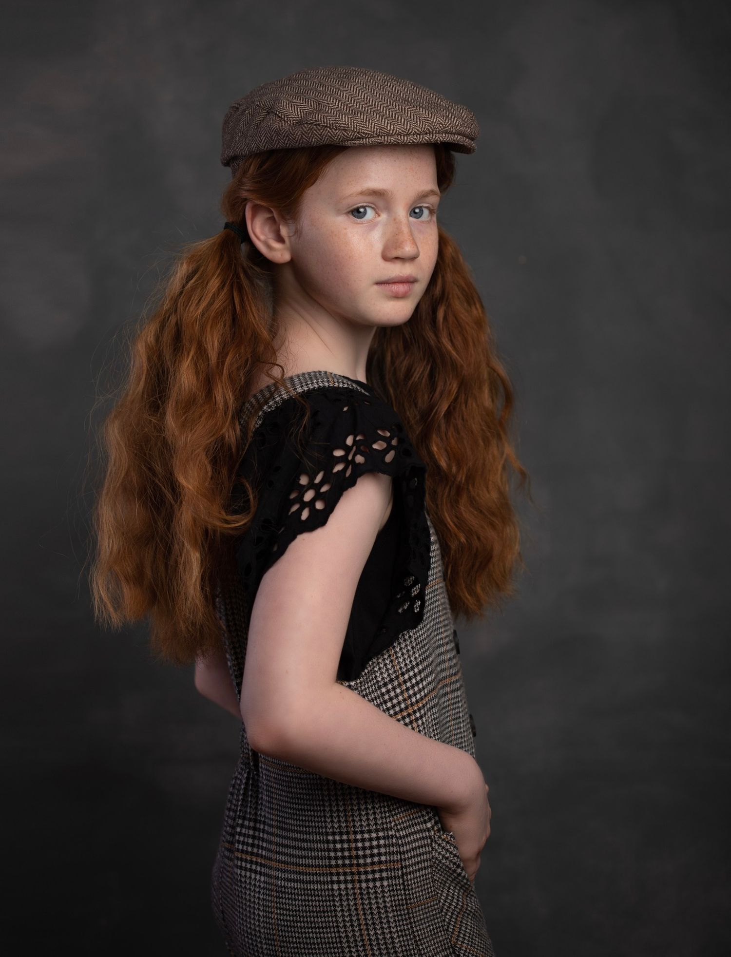 Vintage style portrait series showing dramatic poses in a dark studio with newsboy cap and checkered outfit.