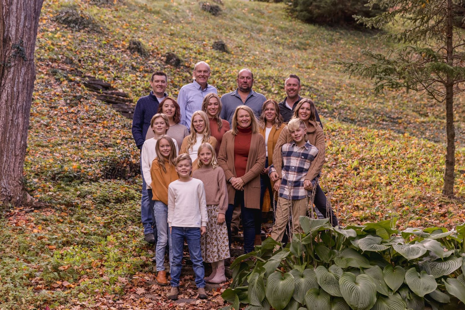 A group gathers near a waterfall in an autumn forest setting for outdoor photos.