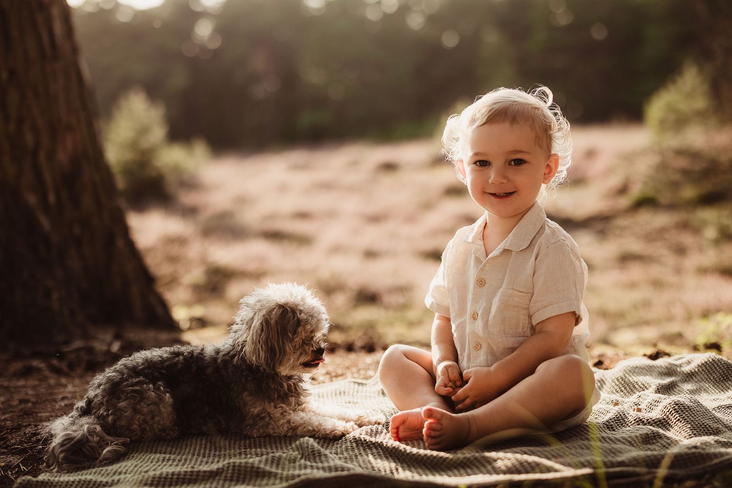 Baby sitting on sandy ground during golden hour photoshoot.