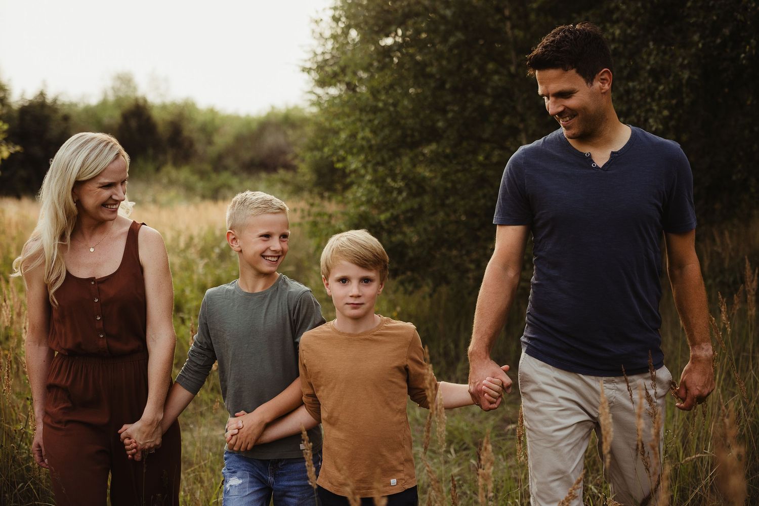 Casual family walking together through a natural meadow setting.