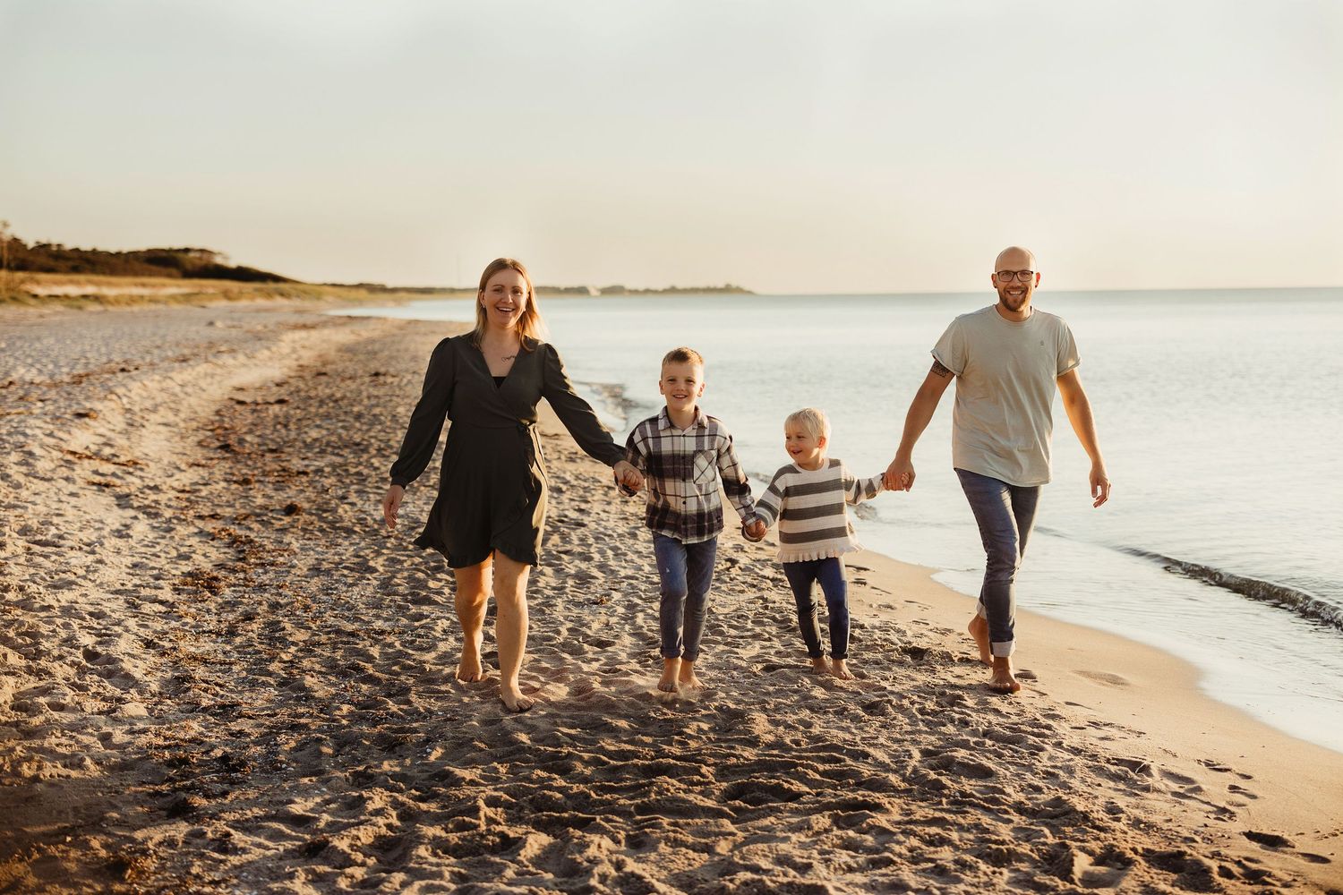 Group walking together on sandy beach with ocean waves in background.