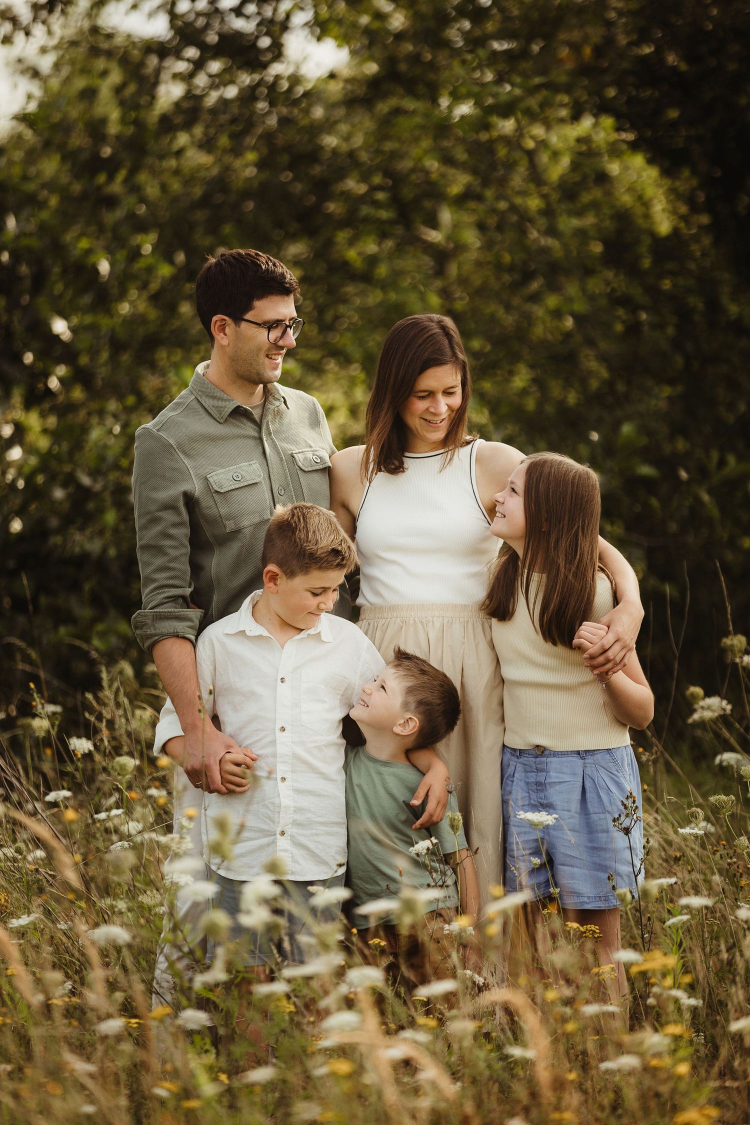 Family portrait in wildflower meadow wearing coordinated neutral summer outfits.