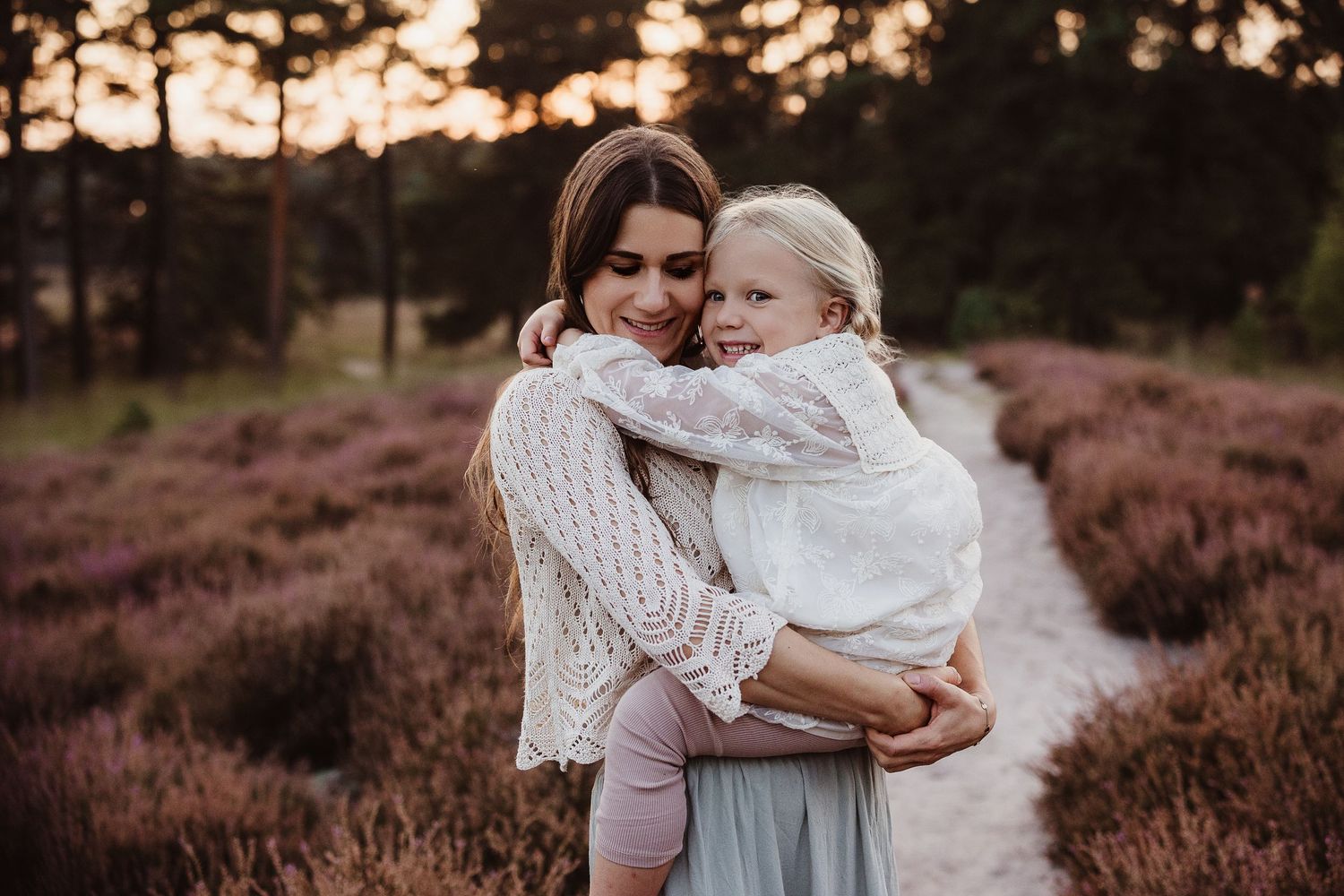 Family enjoying a sunset moment together in a field of purple heather flowers.