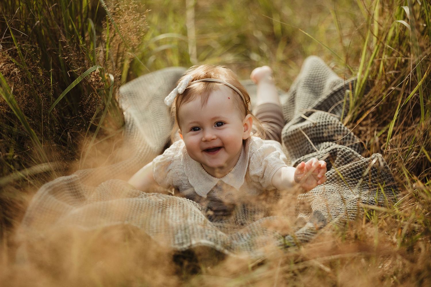 Sweet candid moments captured in tall grass during golden hour.