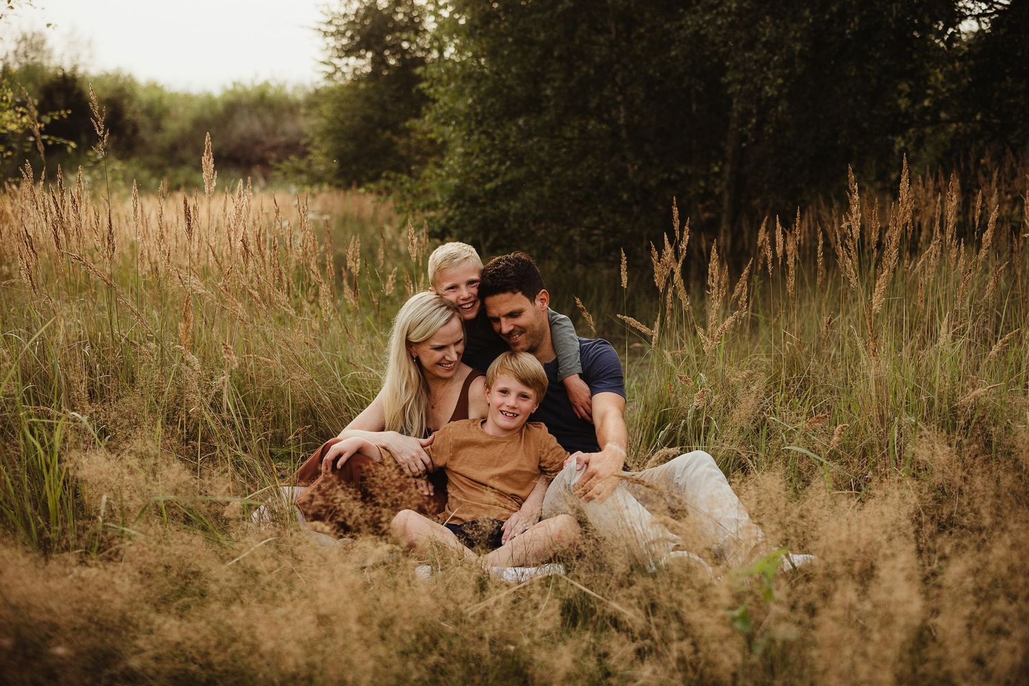 Intimate family portrait session in tall grass during sunset.