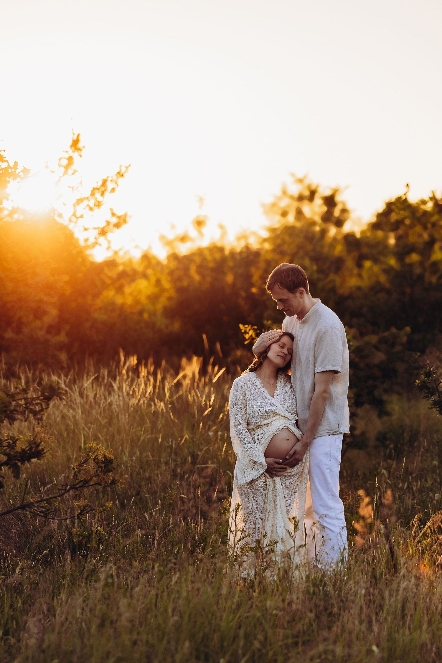 Romantic sunset maternity session in a field of tall grass and wildflowers.