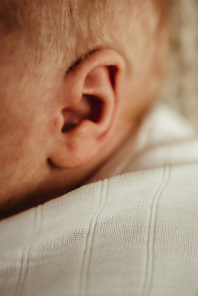 Close-up macro photography sequence of a baby's ear showing fine details and soft skin against white fabric.