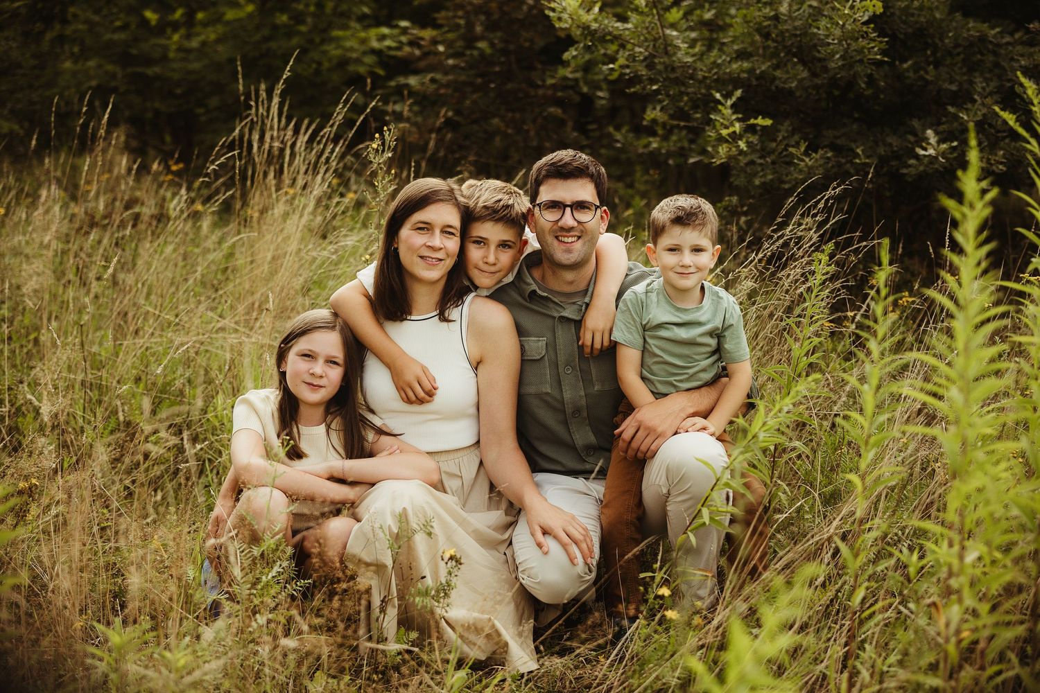 Family portrait session in tall grass with natural summer lighting.
