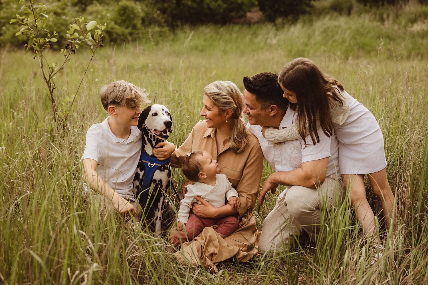 Family sitting together in a natural meadow setting during summer.