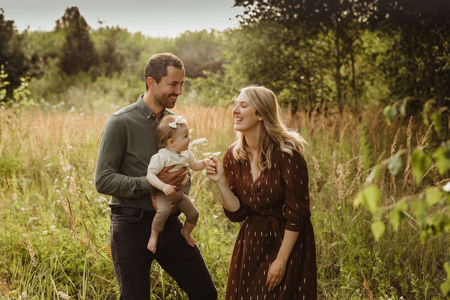 Family sharing playful moments together in a sunlit meadow.